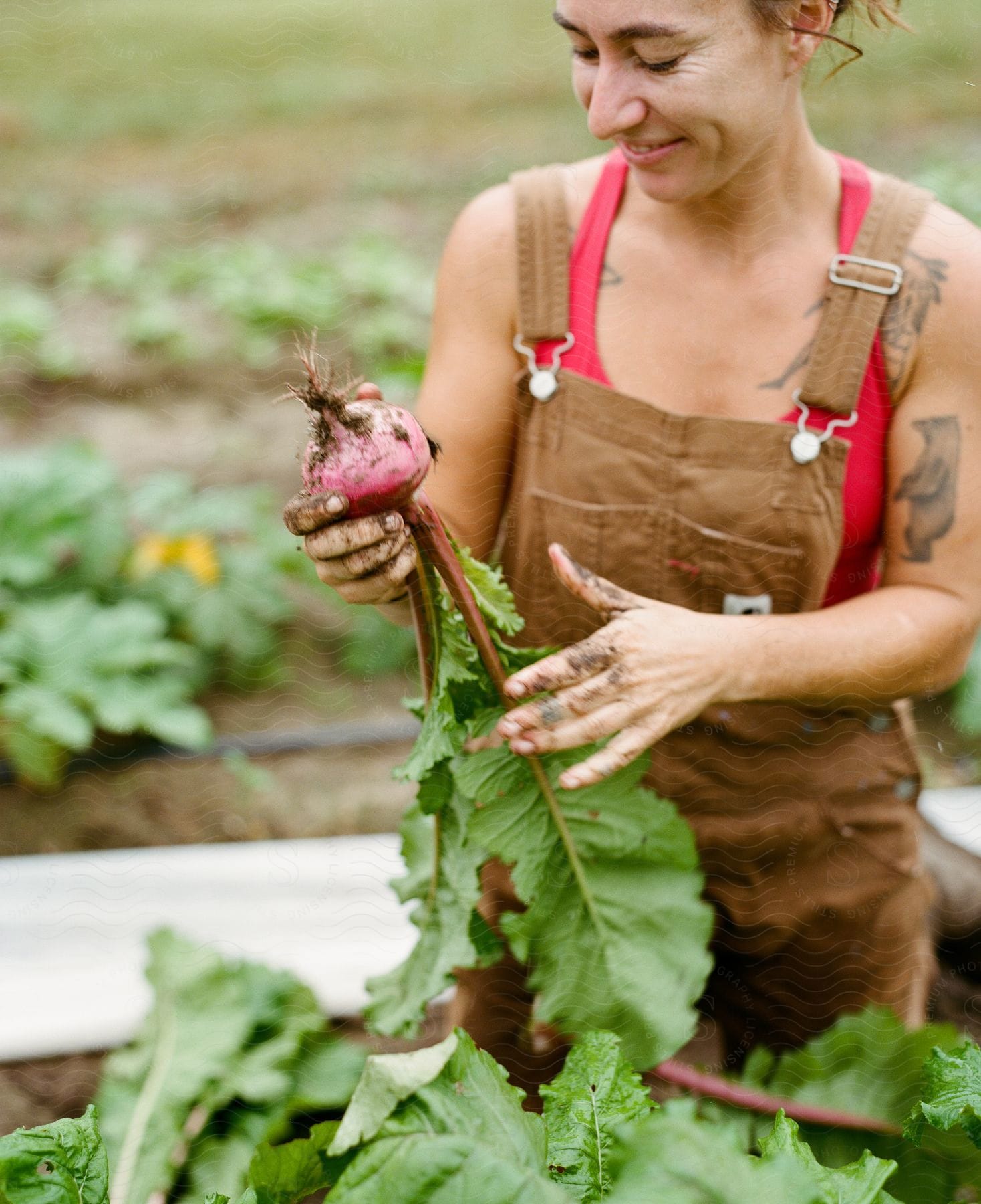 A woman stands in a garden smiling as she holds a turnip