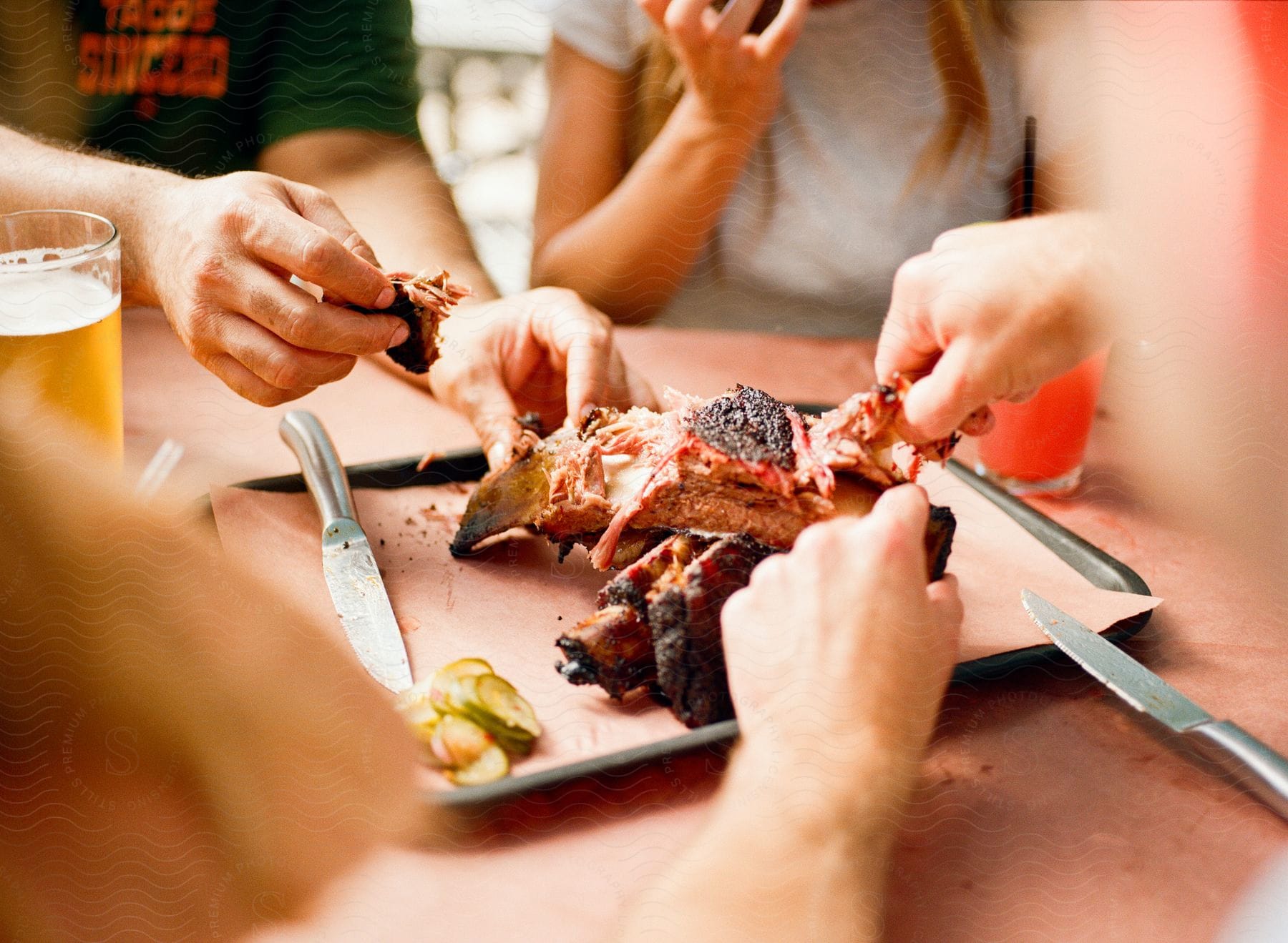 A group of friends sitting at an outdoor table sharing a rack of ribs and drinks