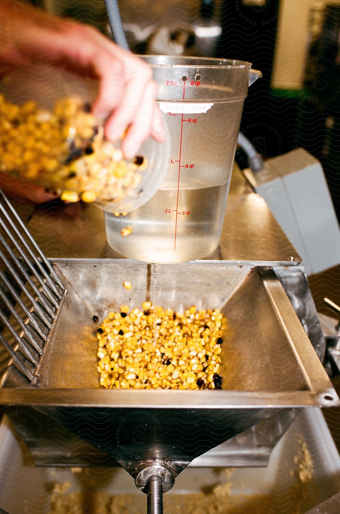 A person pouring corn and water into a machine to cook.