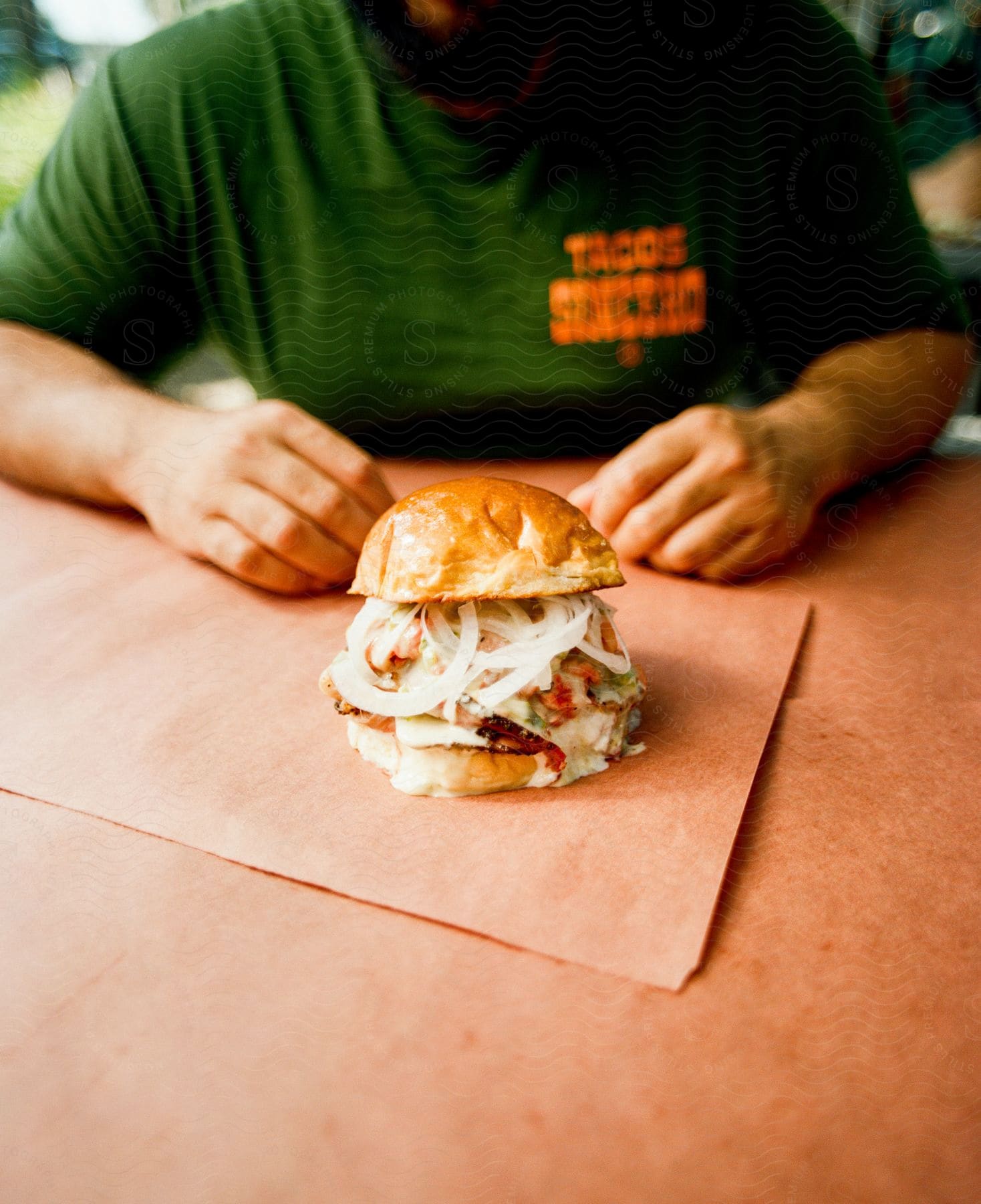 A loaded sandwich served on a brioche bun sits in front of a customer on a paper towel