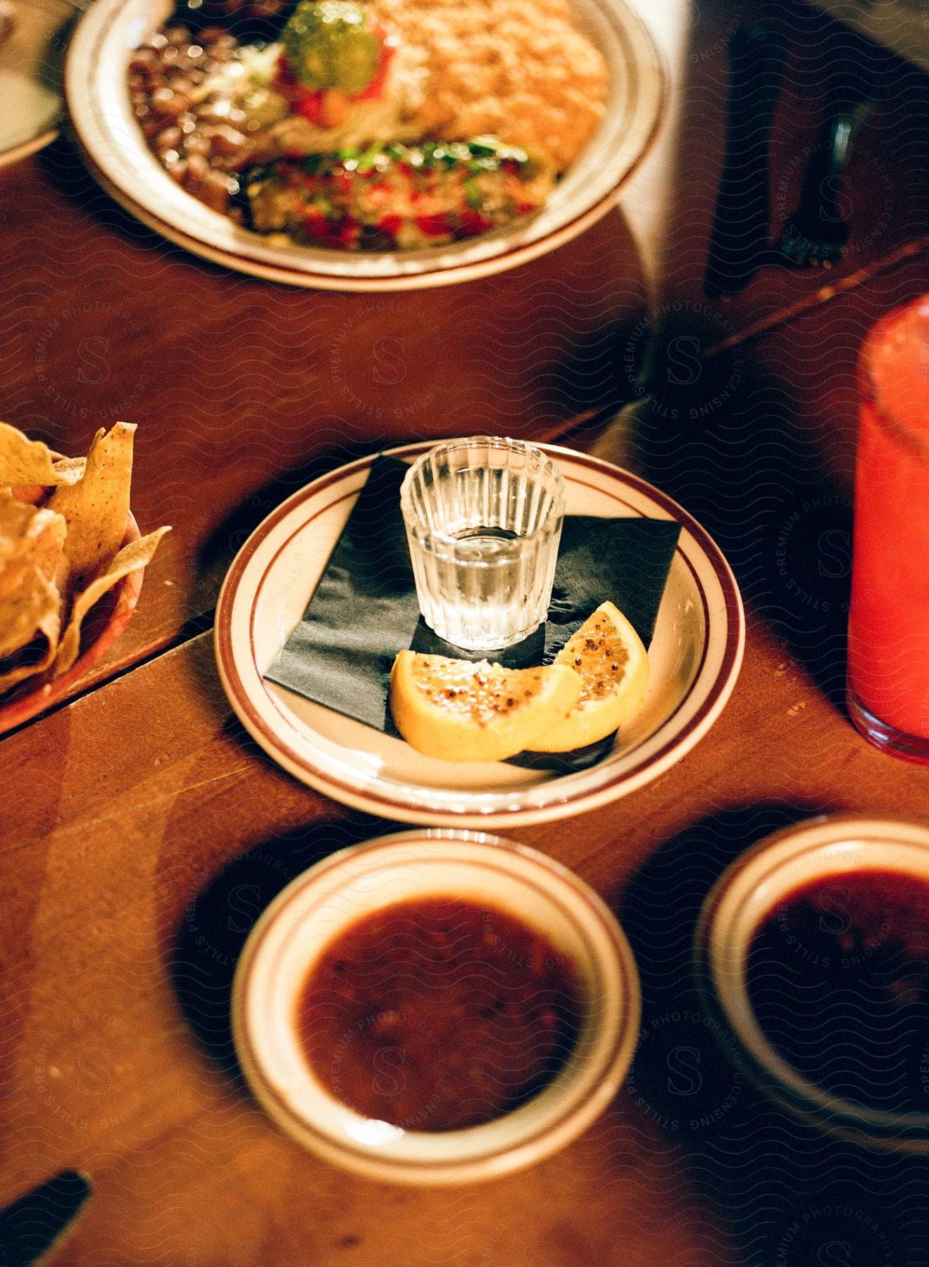 Presentation of a wooden table with a shot, sauces, and nachos.