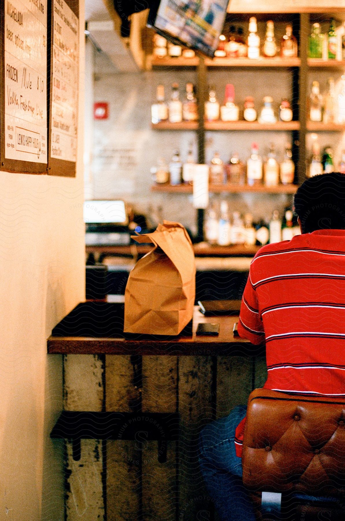 Man sitting in a chair with his back to the camera in a restaurant.