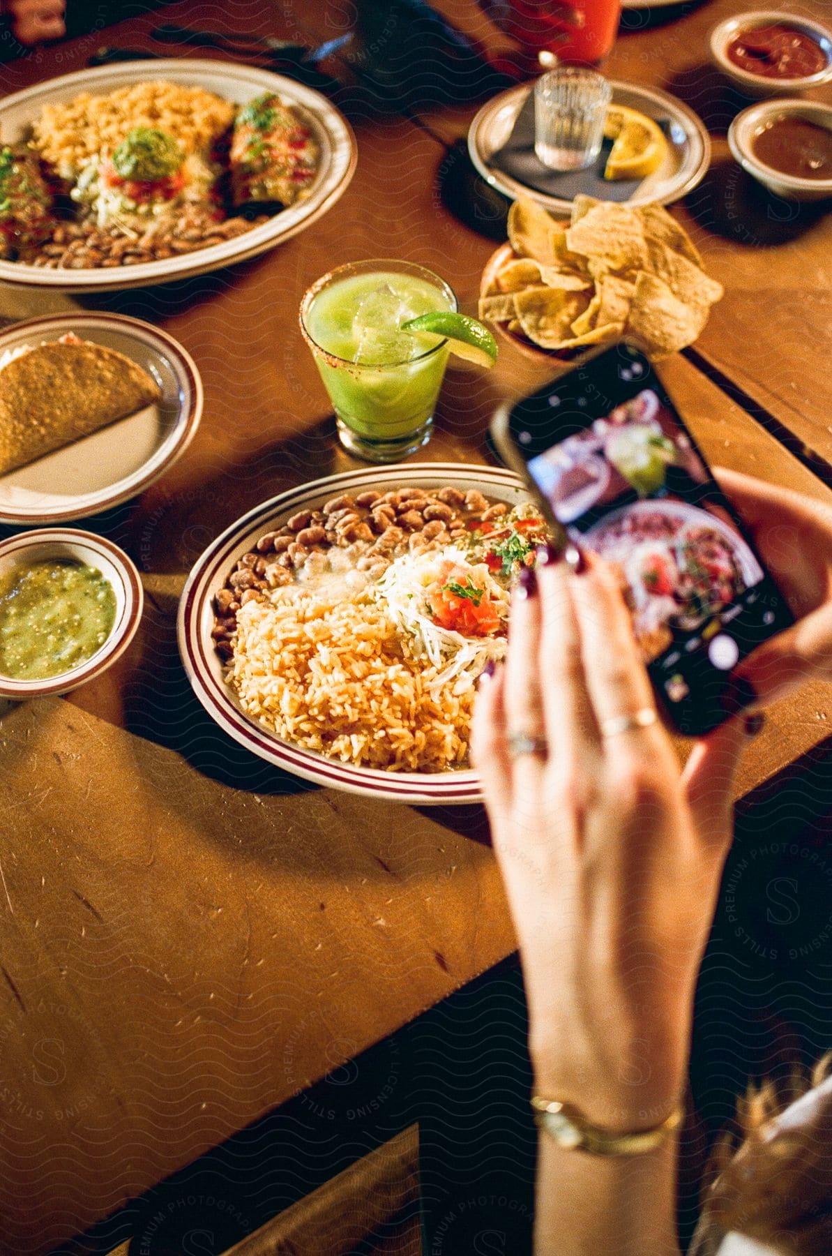A woman taking a photo of an Indian dish including rice and beans.