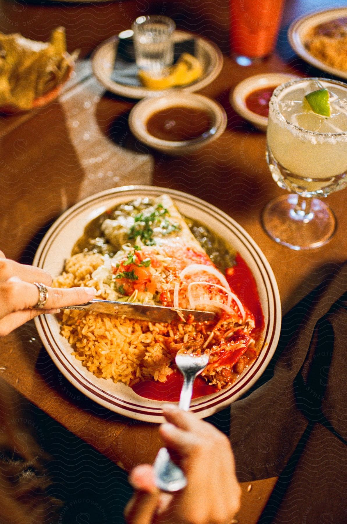 A woman holds a knife and fork as she sits at a table and eats