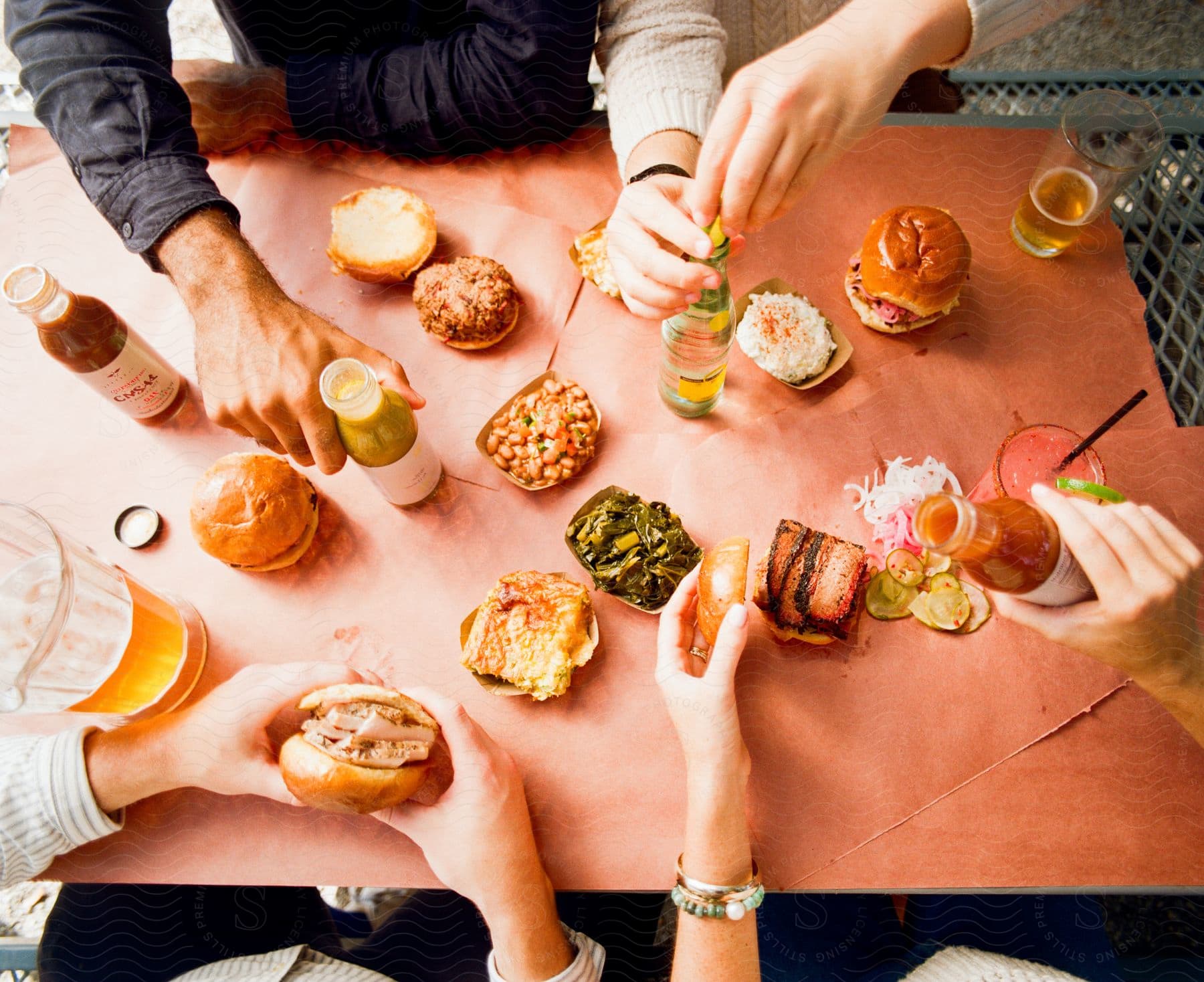 Four people preparing and eating hamburgers and having non alcoholic drinks.