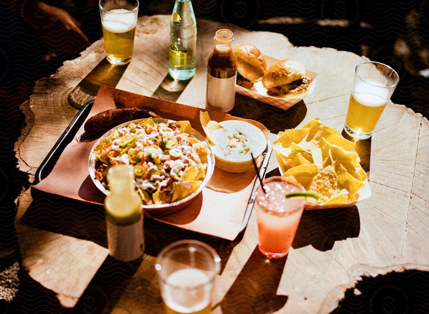 Loaded nachos sliders chips and salsa kielbasa beers and drinks on a tree stump table at Lewis Barbecue In South Carolina