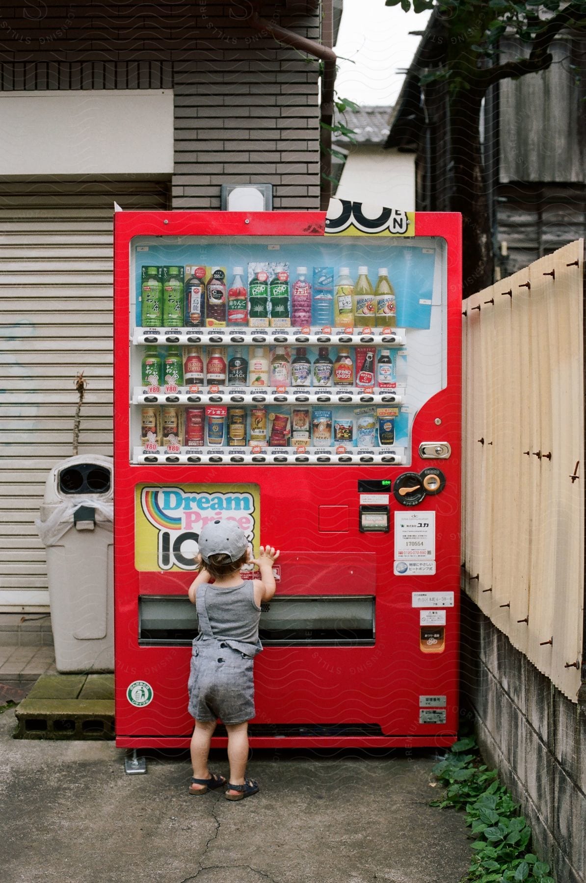 A baby reaching for a drinks vending machine.