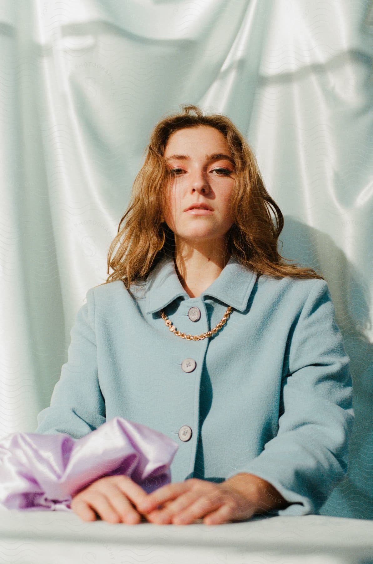 A woman sits outside wearing a light blue coat