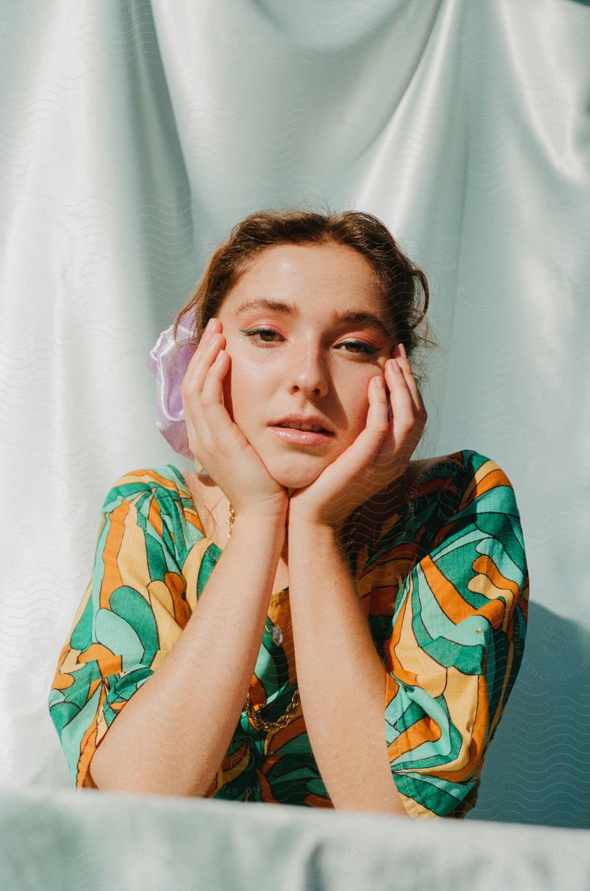 A woman sits with her hands around her face