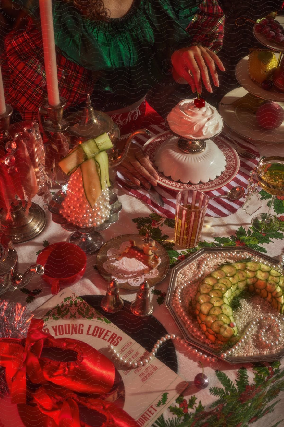 Stock photo of a female wearing a green dress dips a cherry into whipped cream at a christmas holiday table.