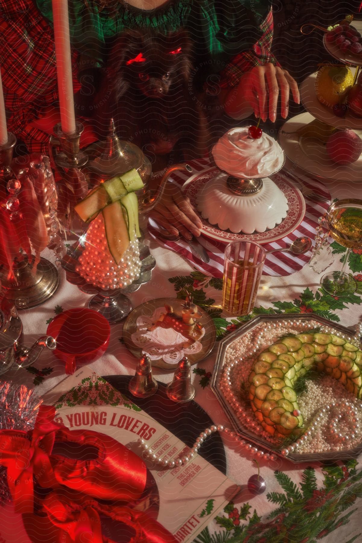 A woman's hand is taking a cherry from the top of a cake at a table filled with Christmas desserts