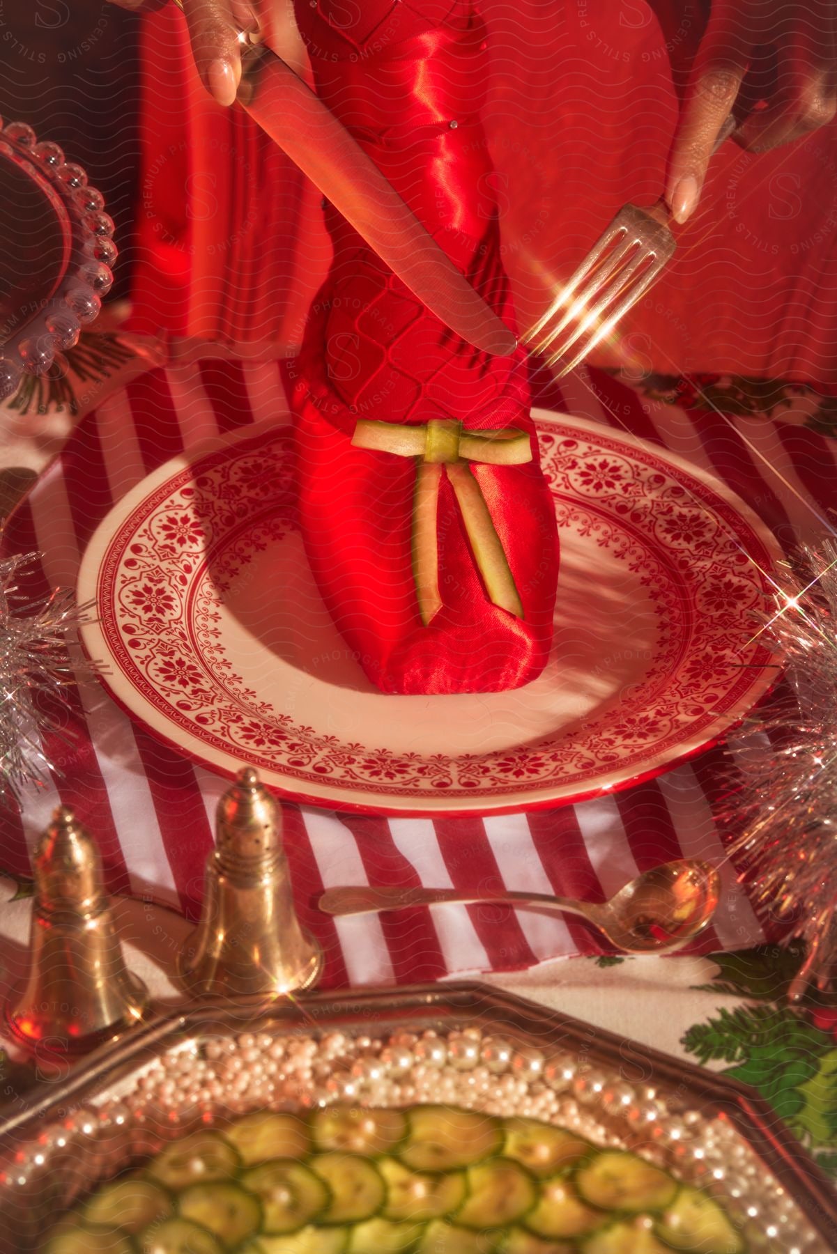 A whimsically decorated holiday table setting featuring a red napkin folded into a dress design on a plate.