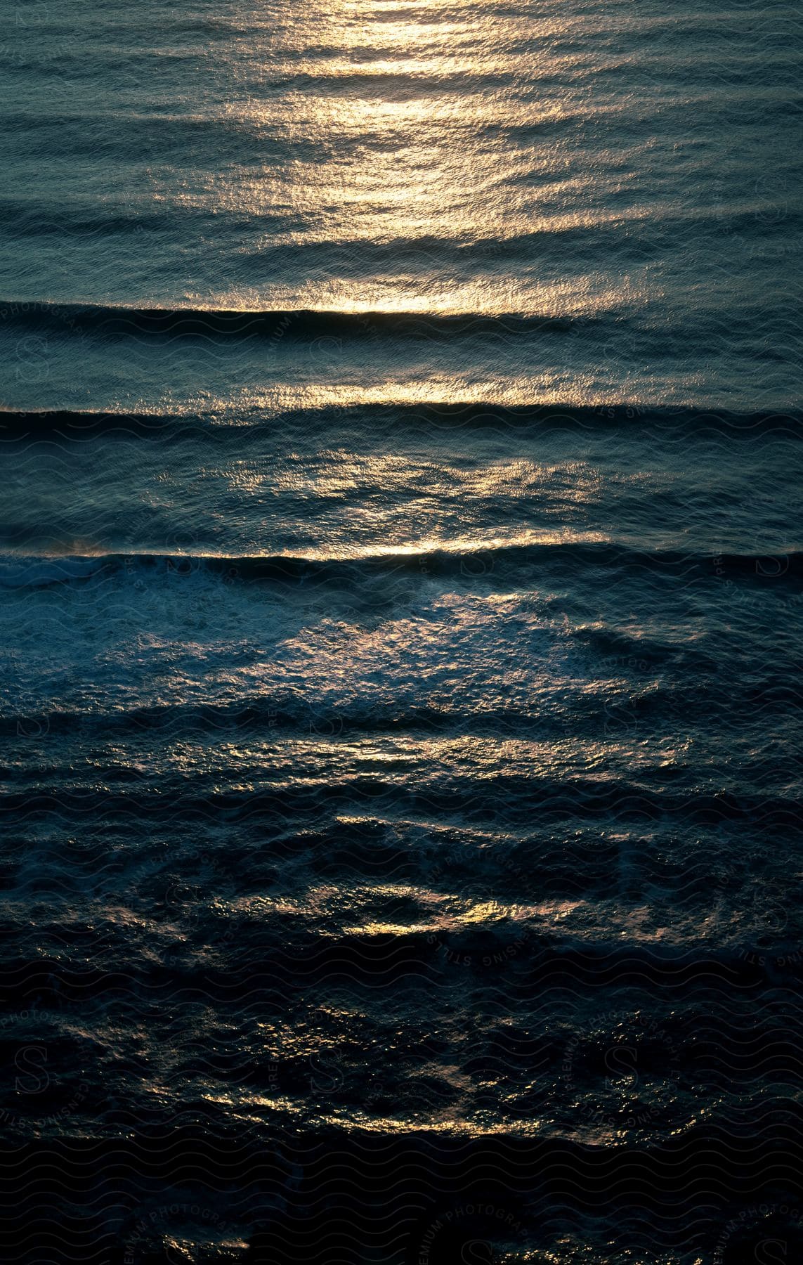 the sun reflection is seen on the ocean as the waves flows in lines