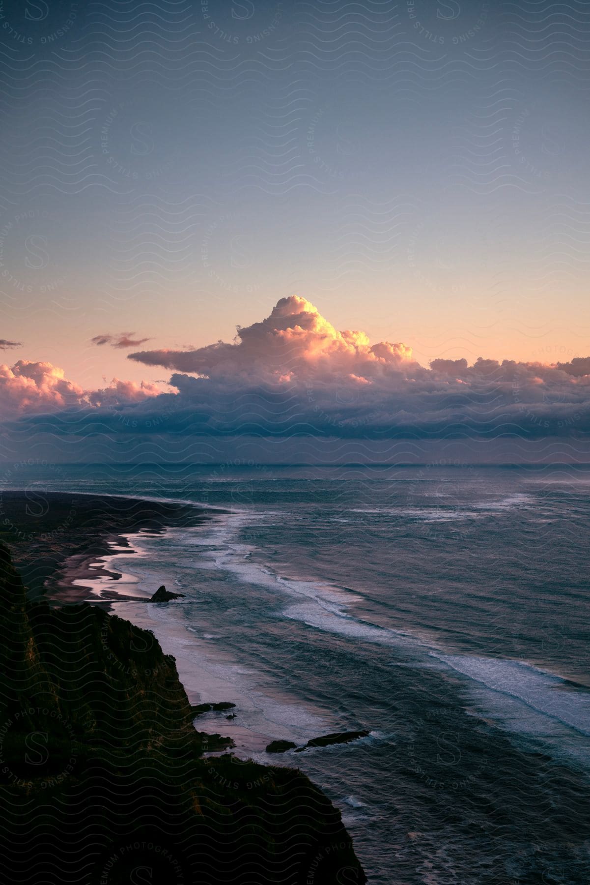 Waves Roll Into Shore As The Sun Shines On Clouds In The Distance