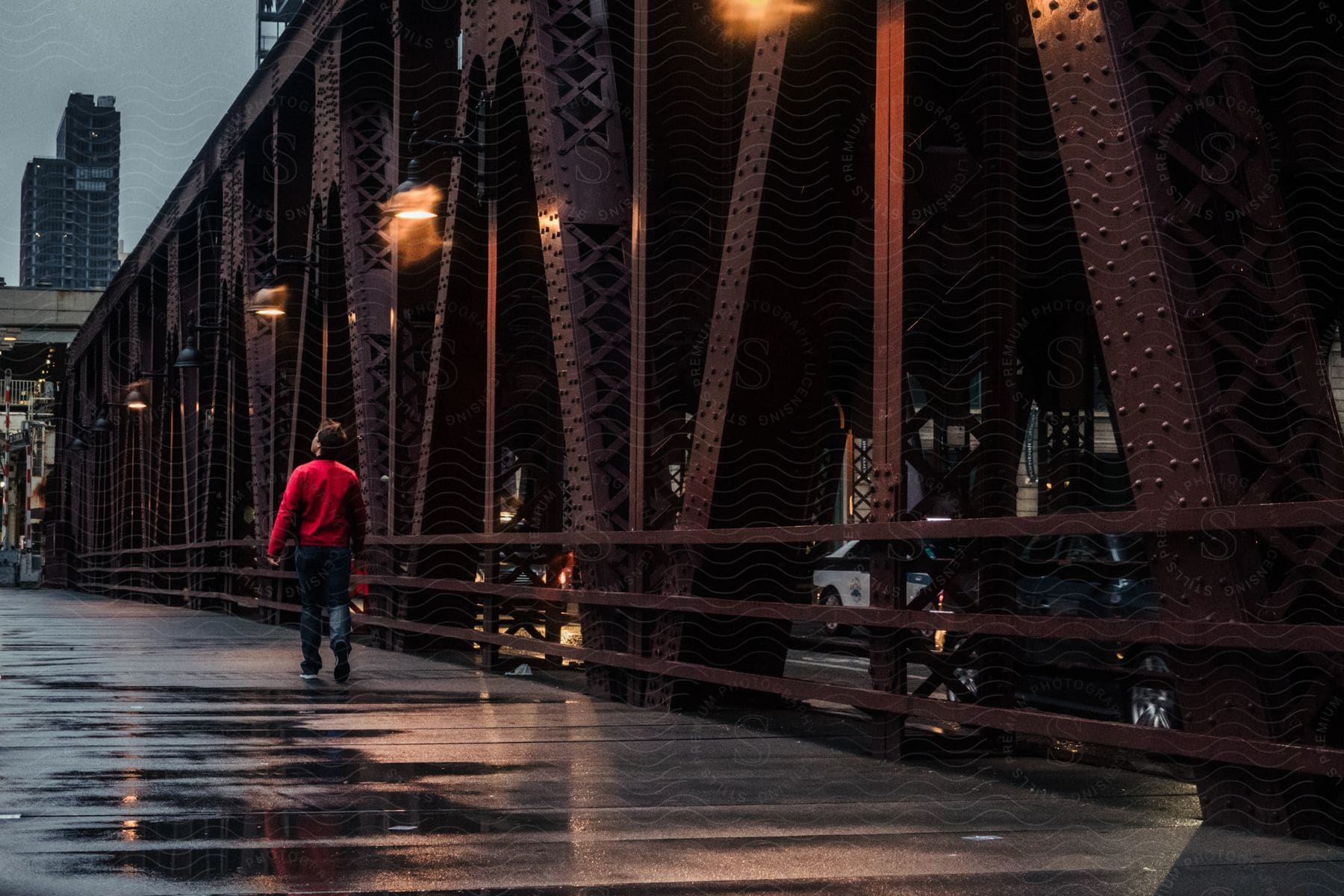 A woman walks across a bridge into town as lights shines on the wet pavement