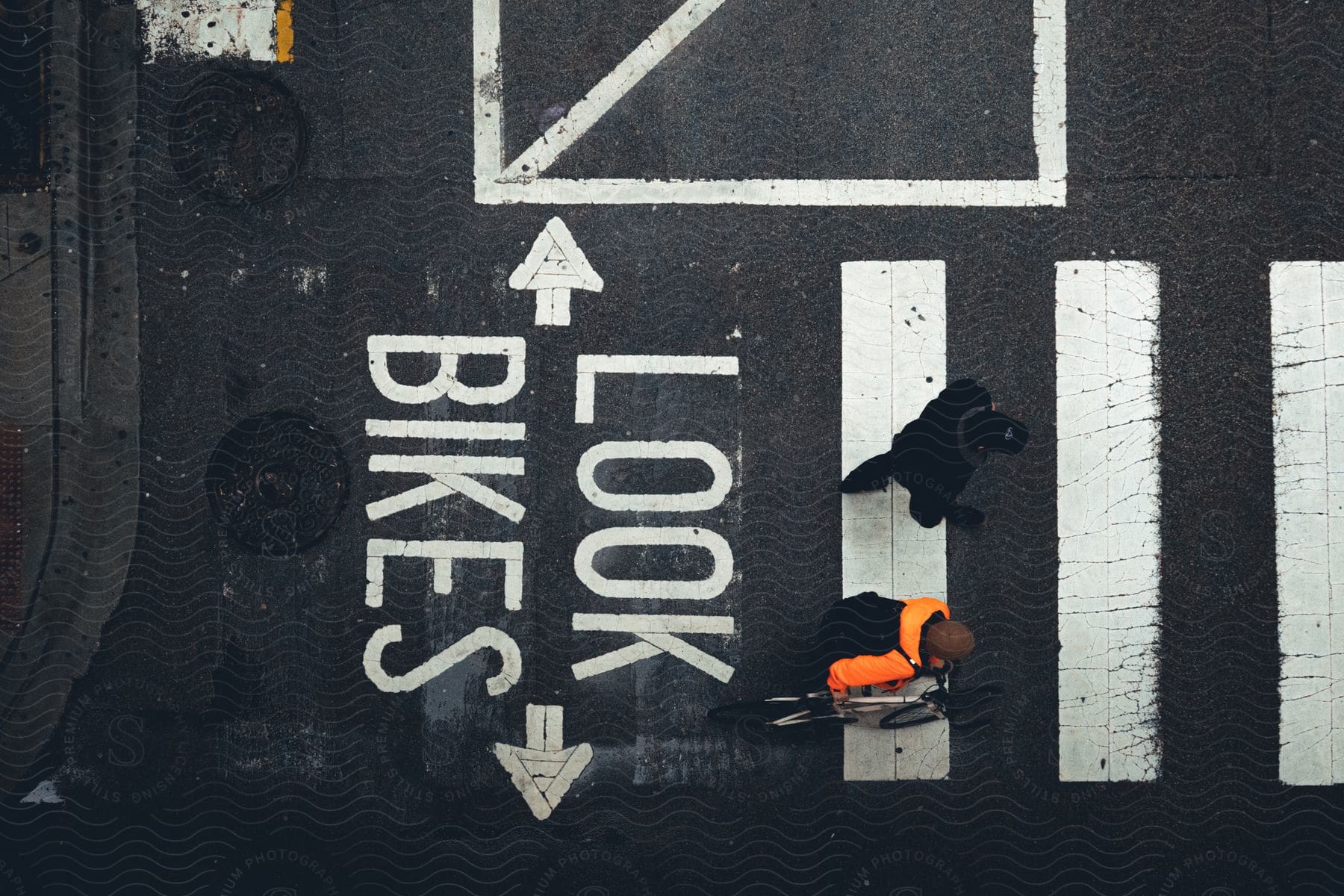 A cyclist in bright clothing follows a city bike lane, passing a "LOOK BIKES" road marking.