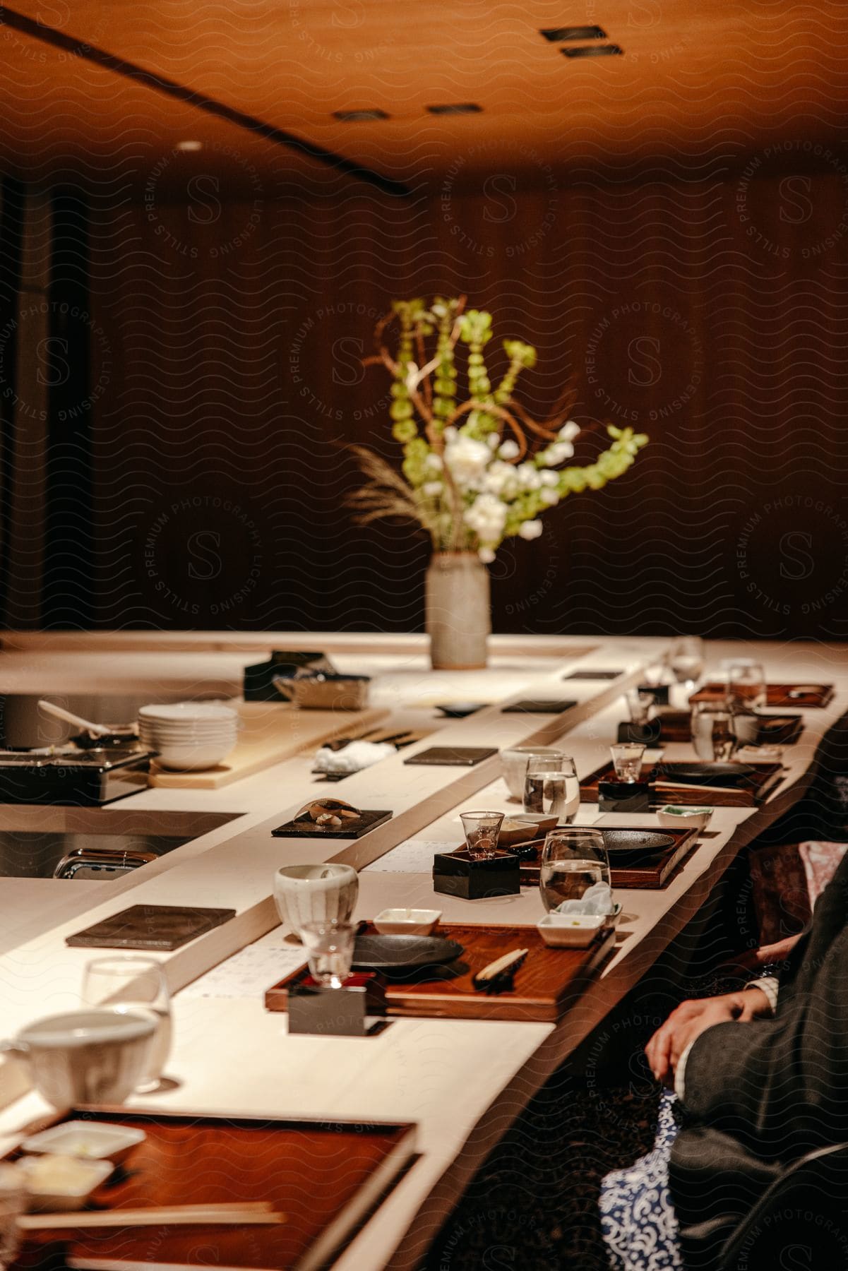 People sit in front of place setting at counter in restaurant.