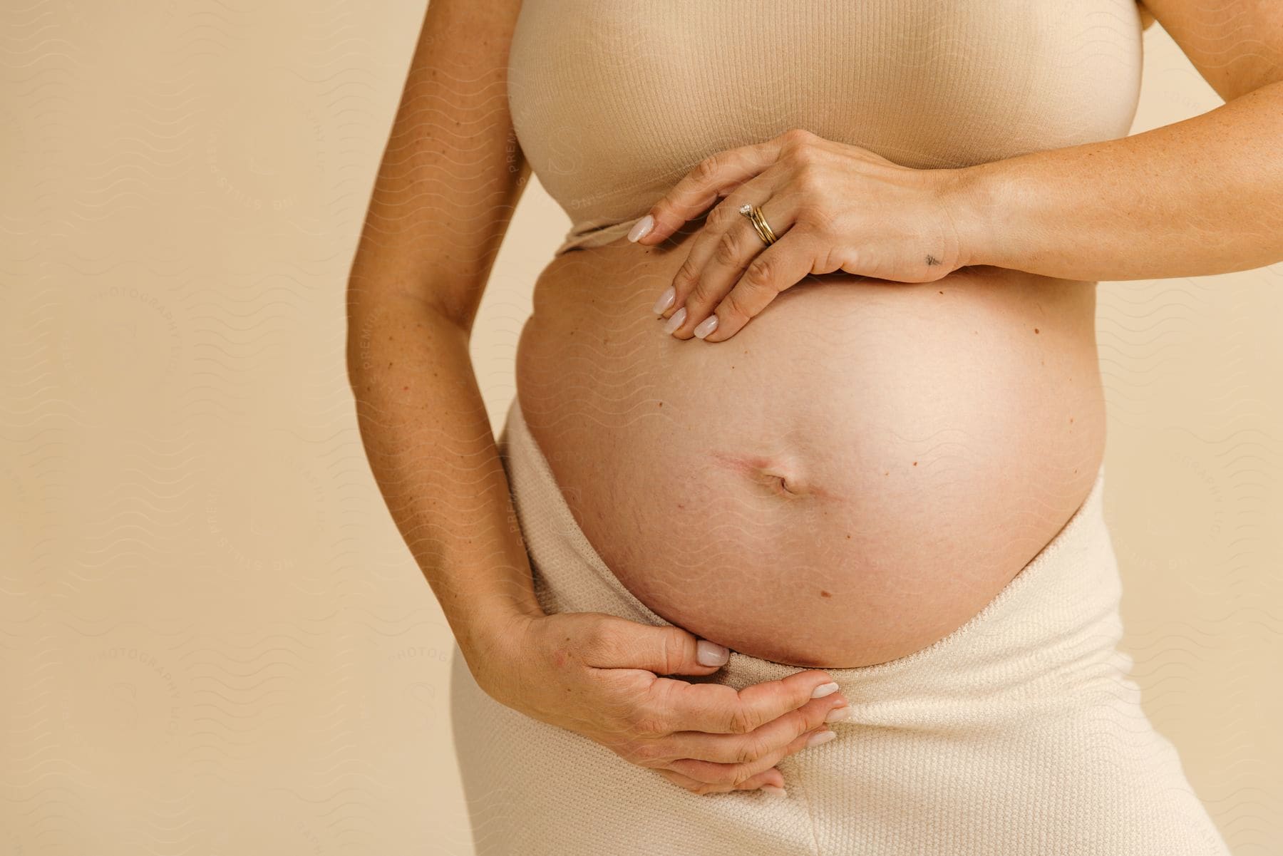 A pregnant woman holds her hands on her belly