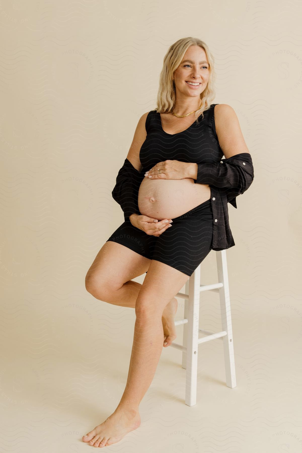 a pregnant woman on barefoot is rubbing her arms on her belly as she smile