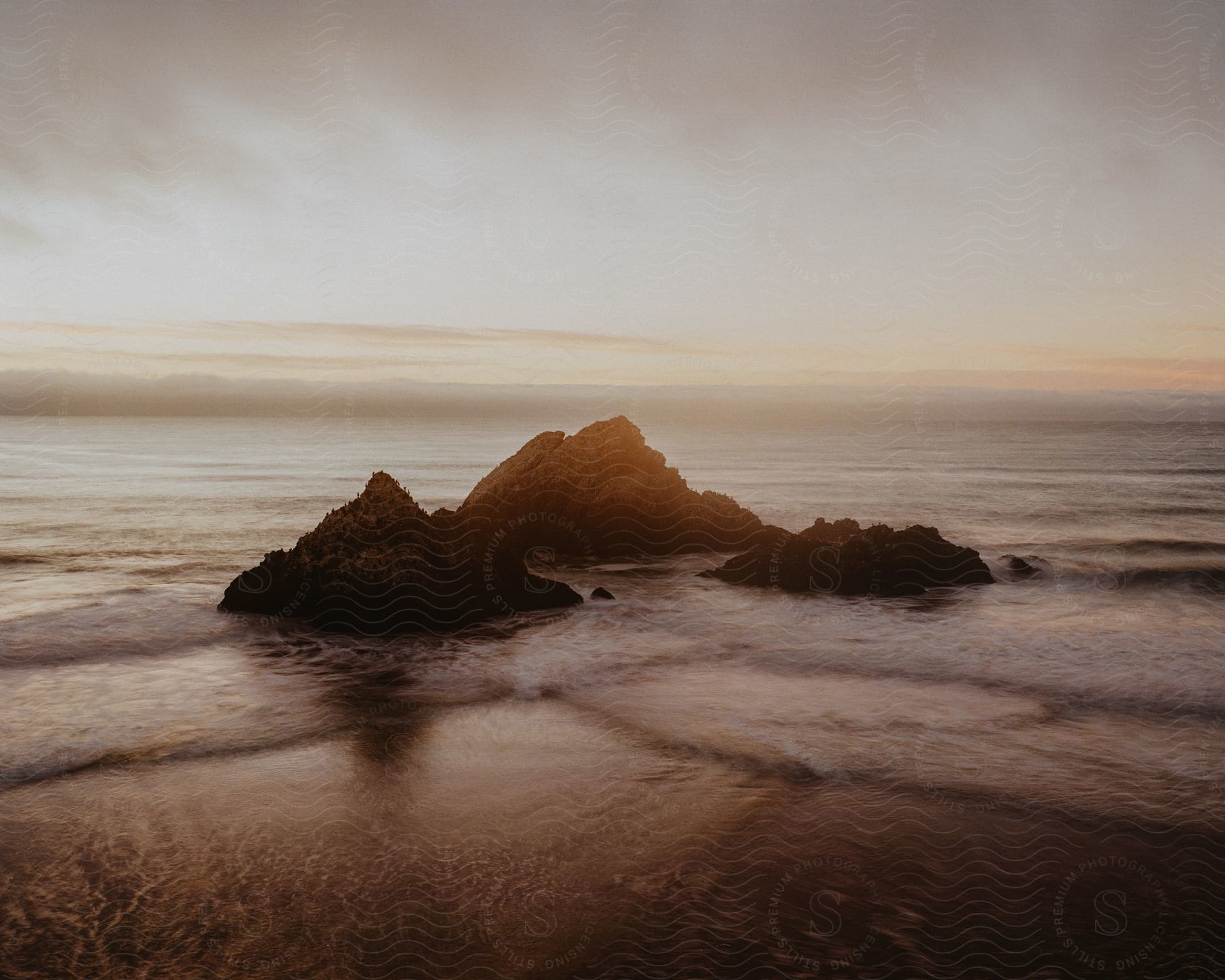 Three large rocks are in the body of water.