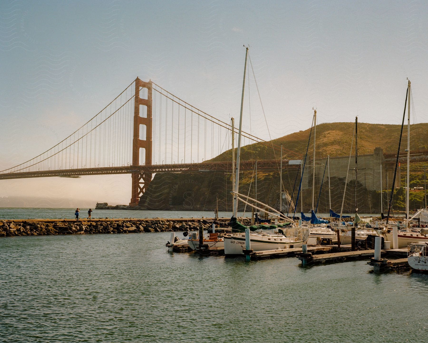 Panorama of boats docked at piers with a view of the Golden Gate Bridge.