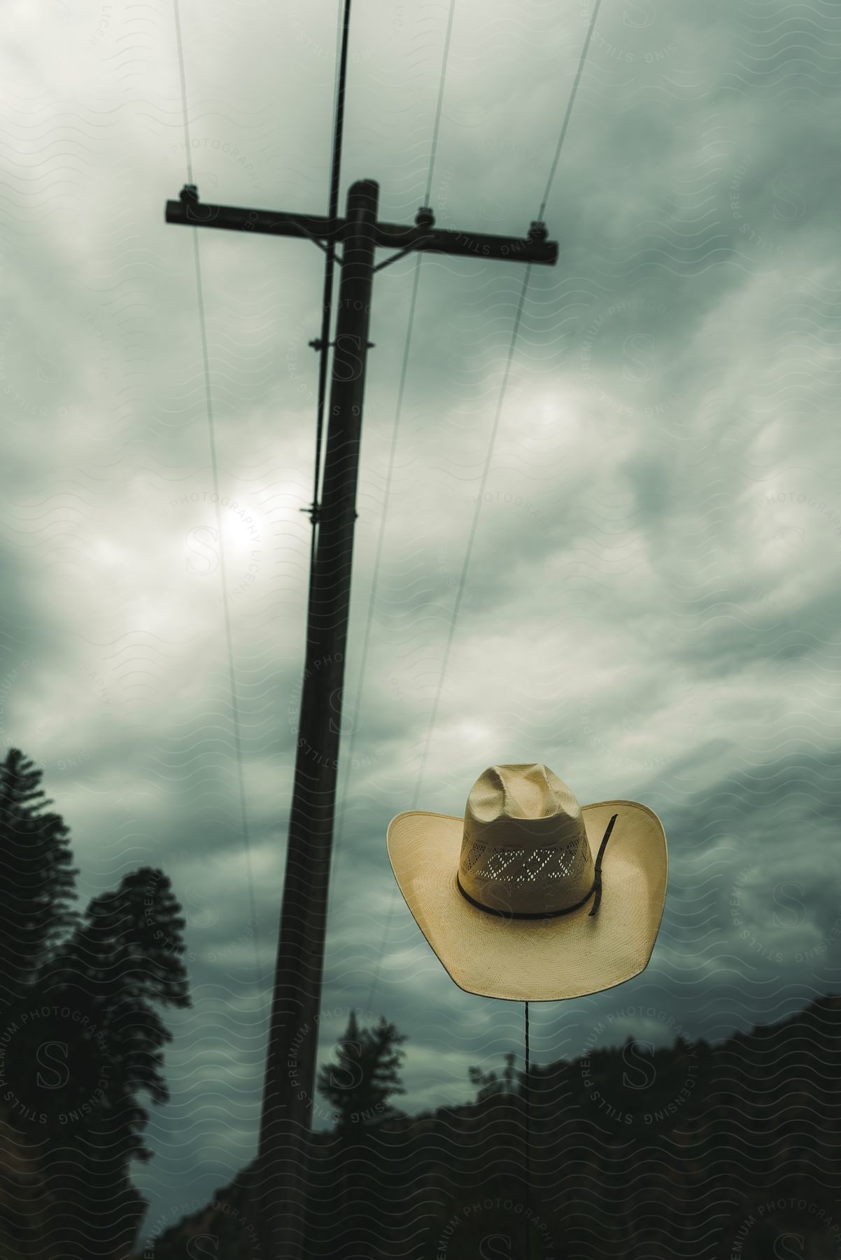 A cowboy hat outdoors on a cloudy day with a power line next to it.