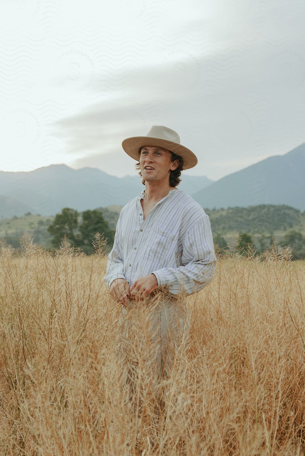 Man in cowboy hat in the middle of a dry grassland during the day