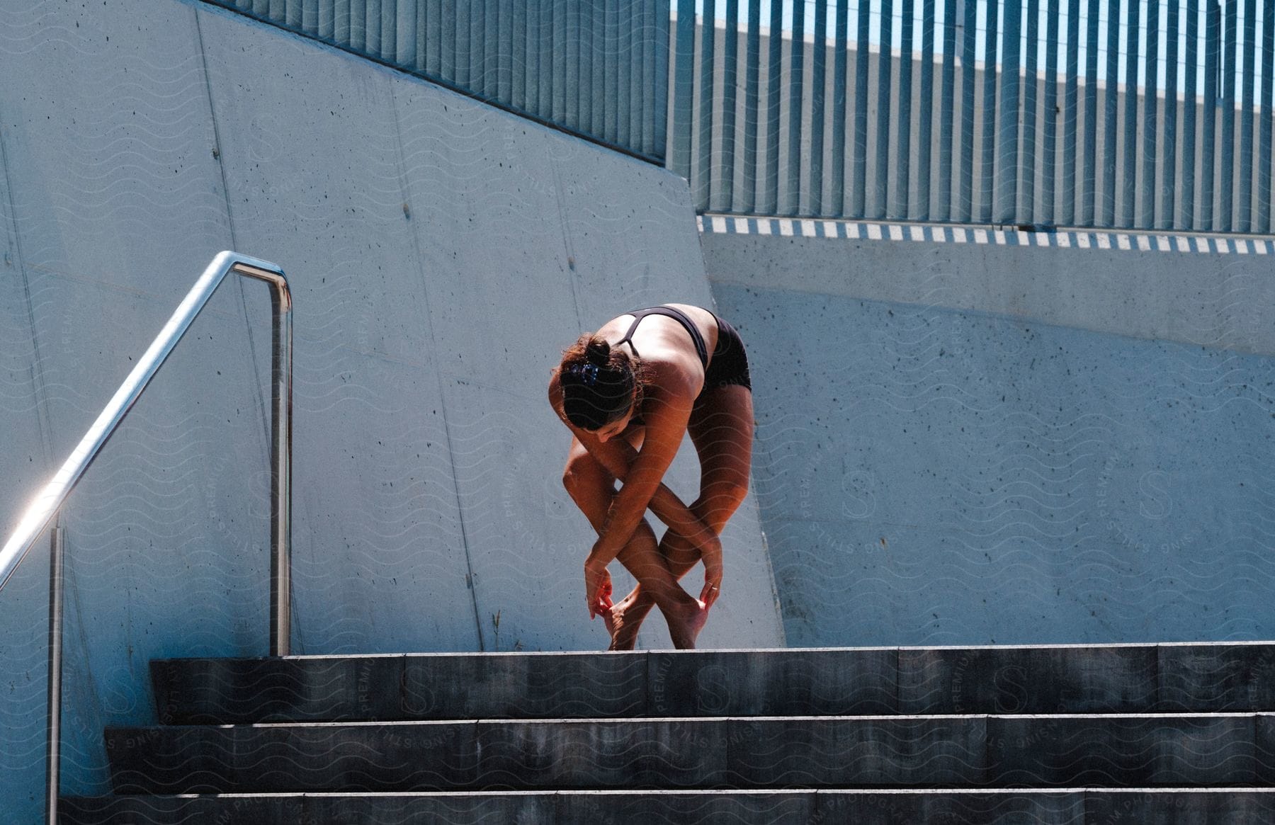 A women is stretching on the top of the stair case.