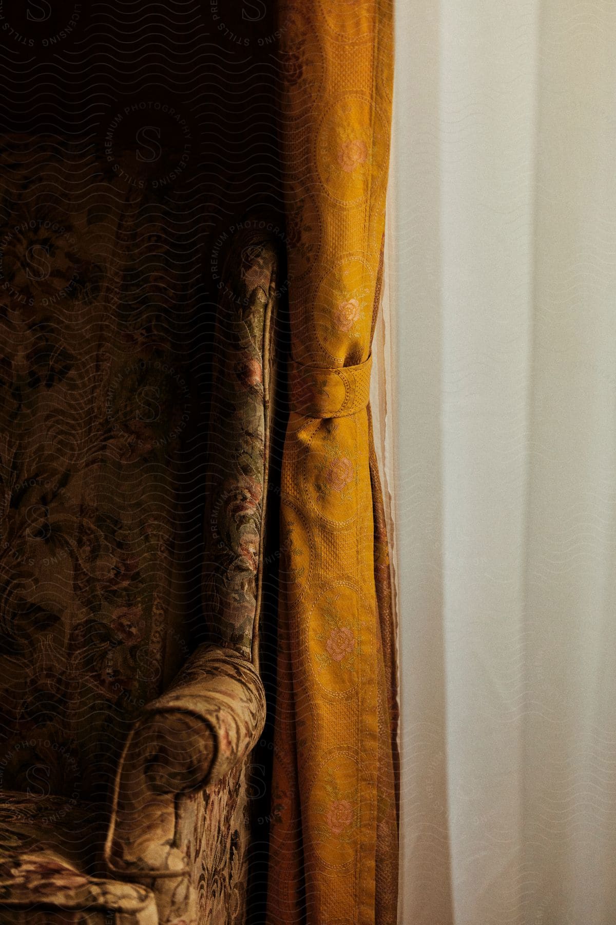 a brown arm chair beside a brown curtain