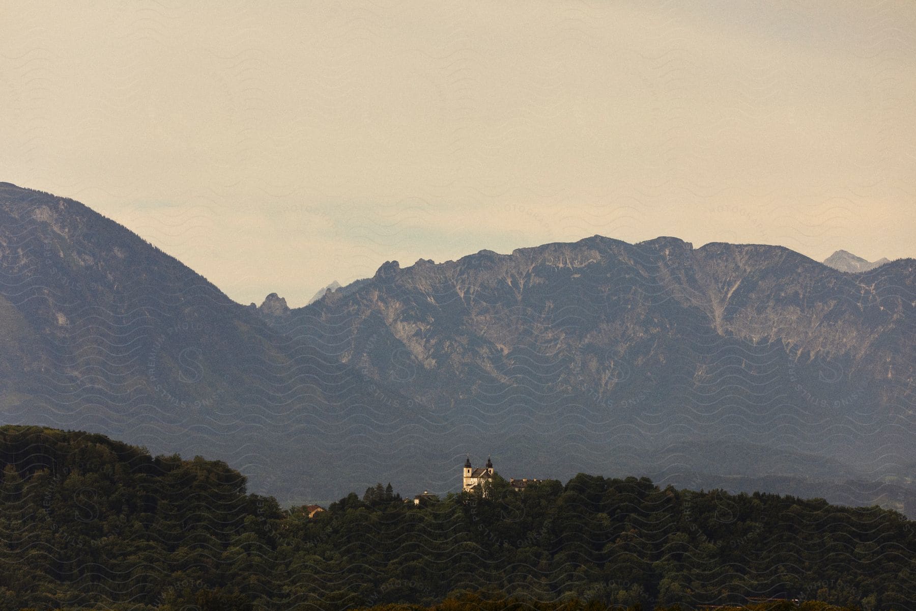 Castle at the edge of a forest overlooking mountains in the distance