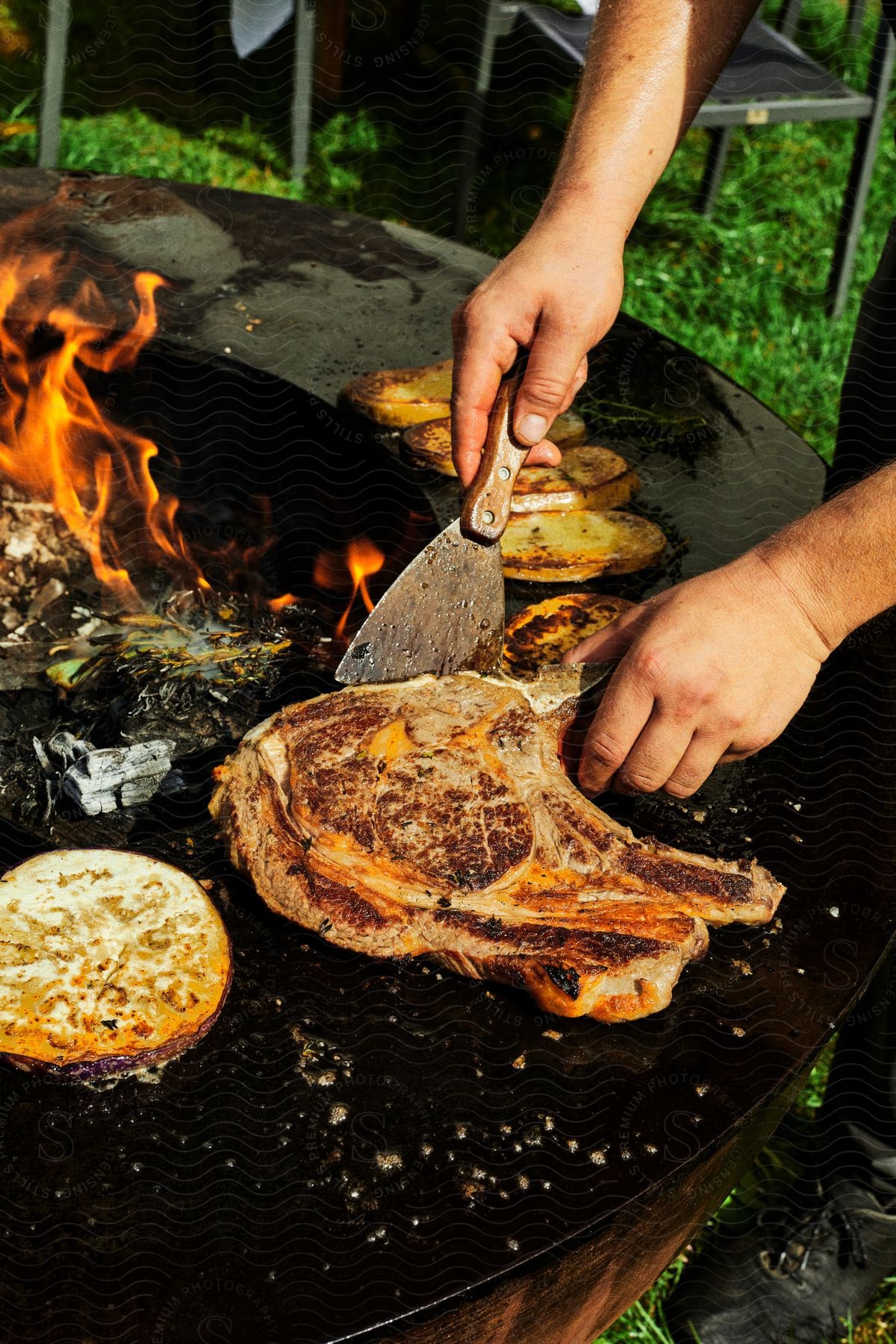 A person cooking meat out on a grill