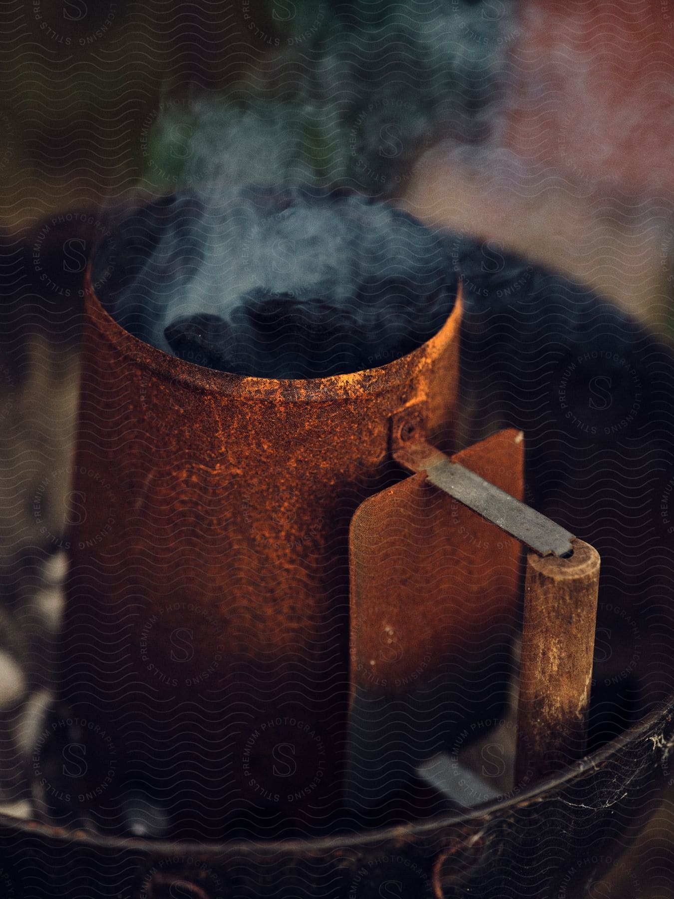 A rusty iron jar with charcoal on a barbecue grill.