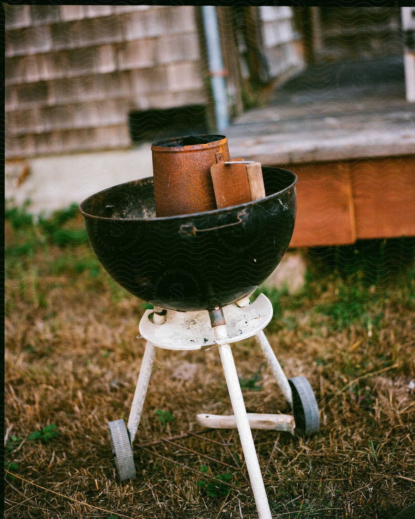 A well-used barbecue grill stands on a lawn, seasoned with memories of summer feasts.