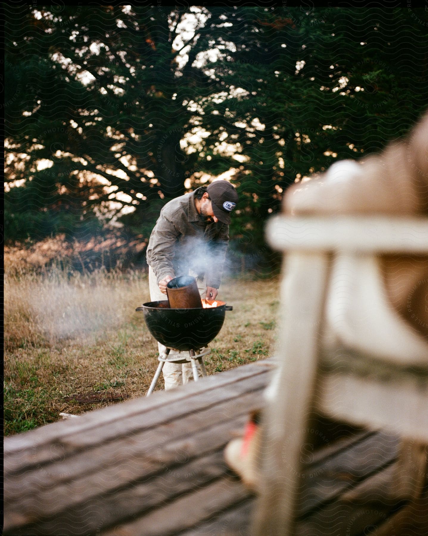 A Man Lighting A Barbecue In A Meadow