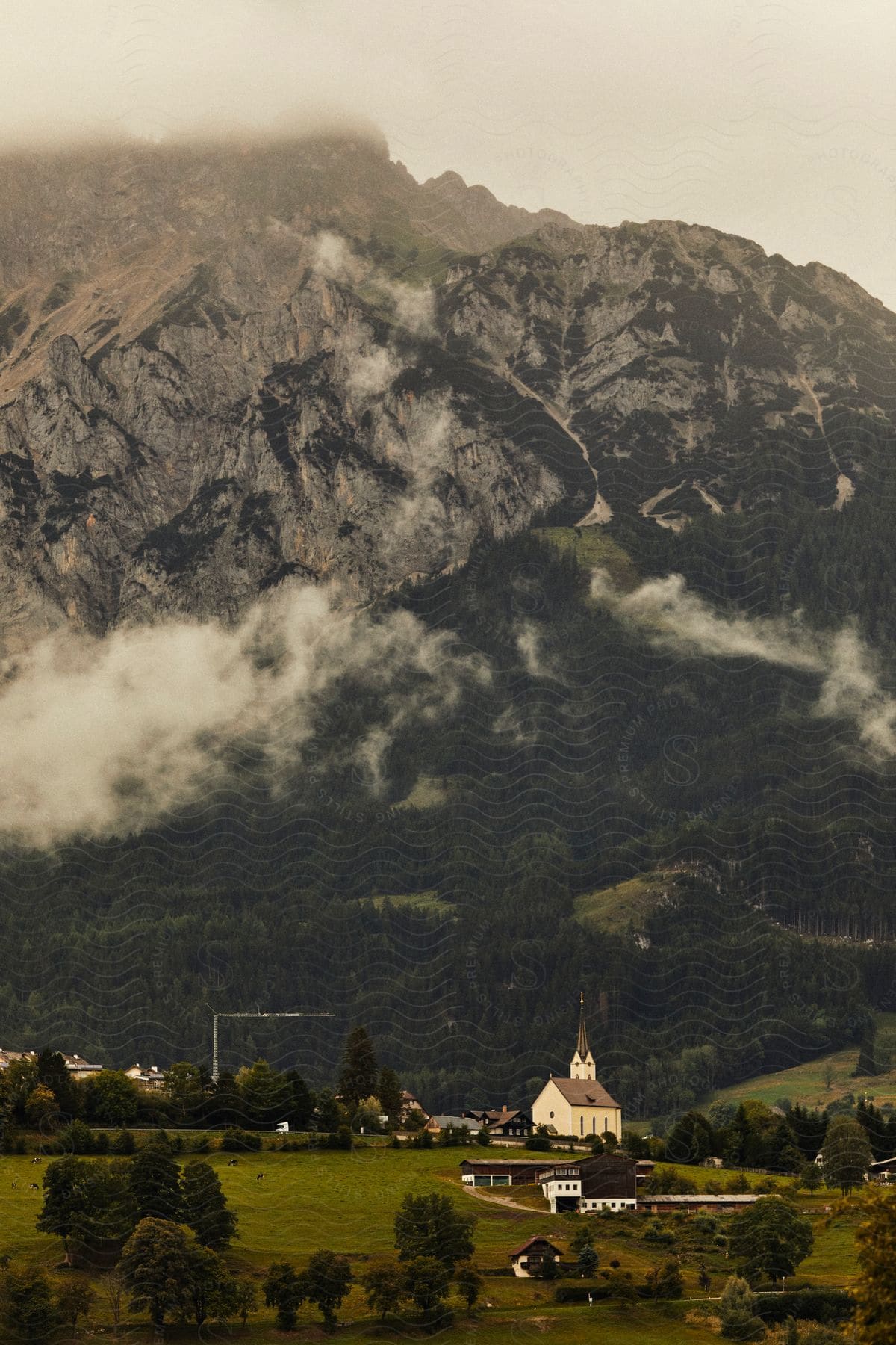 Panorama of a landscape with some houses, church and hills and mountains on a cloudy day