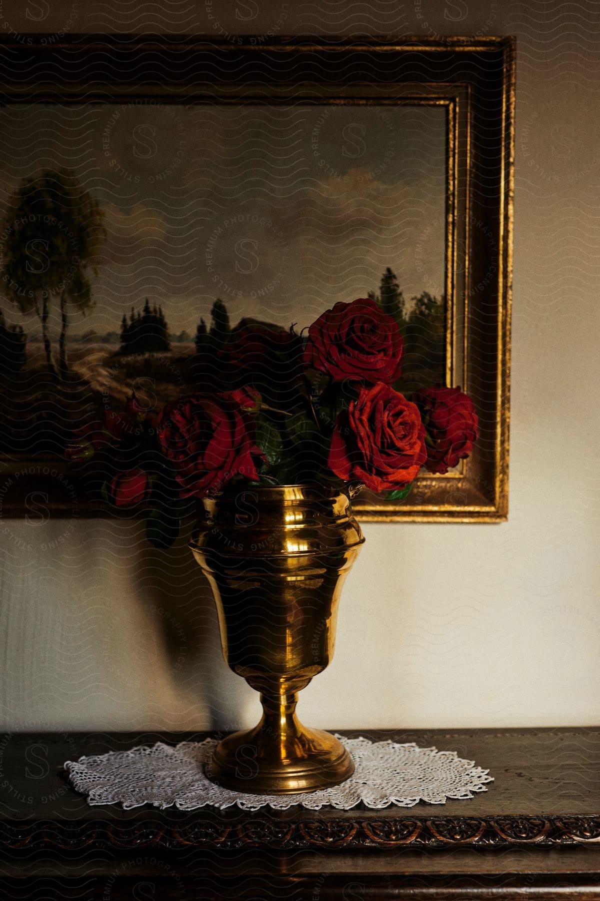 A golden flower vase with red roses decorating a room.