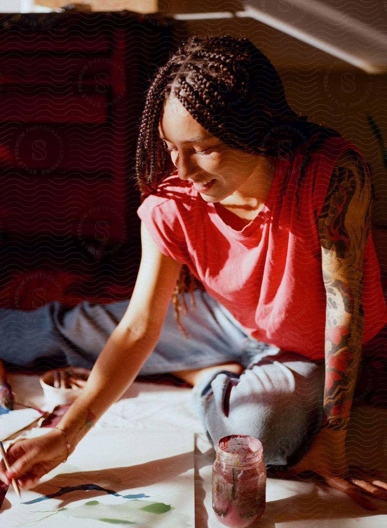 A woman sits on the floor painting a picture