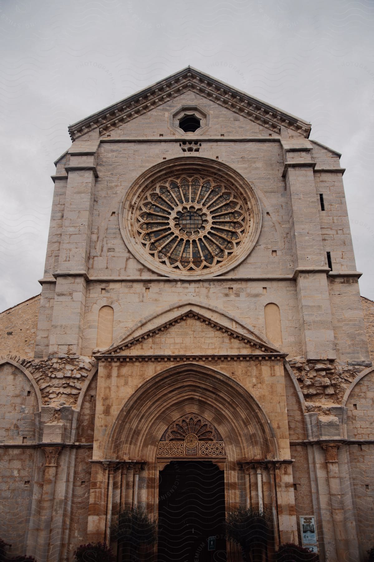 Large stone church entrance topped by a round stained glass window on its towering facade.