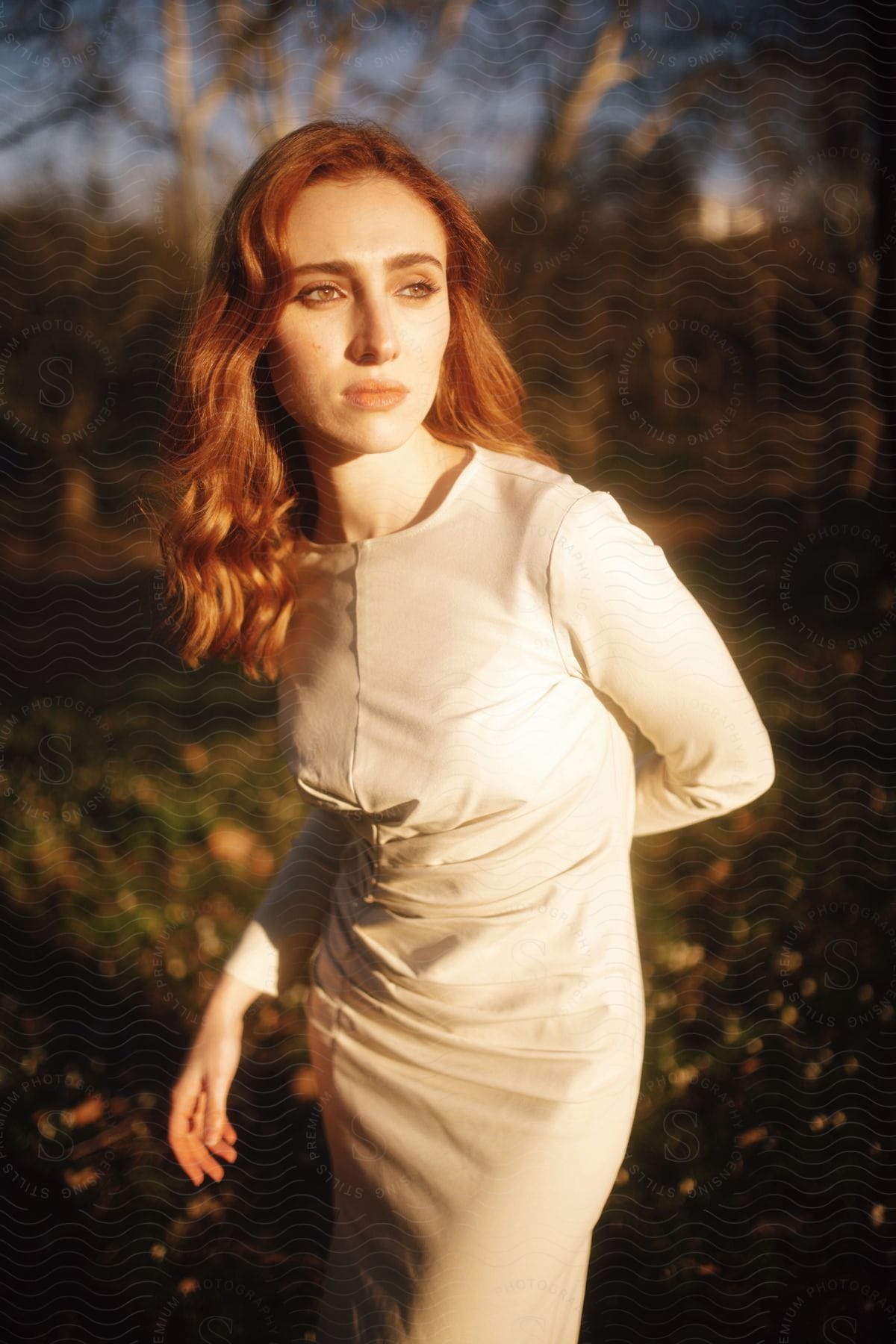 redhead woman standing up outdoors next to a forest during day time