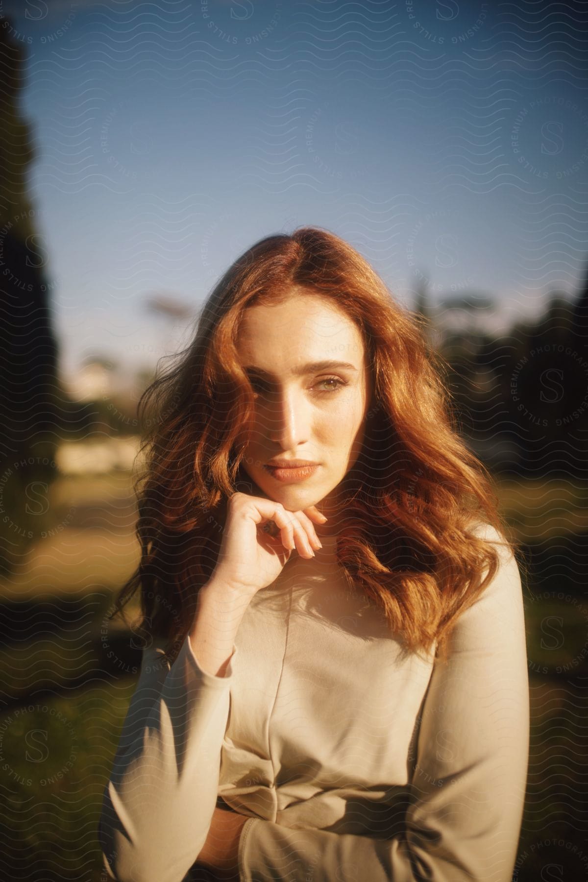 redhead woman outdoors holding her hand to her jaw during day time