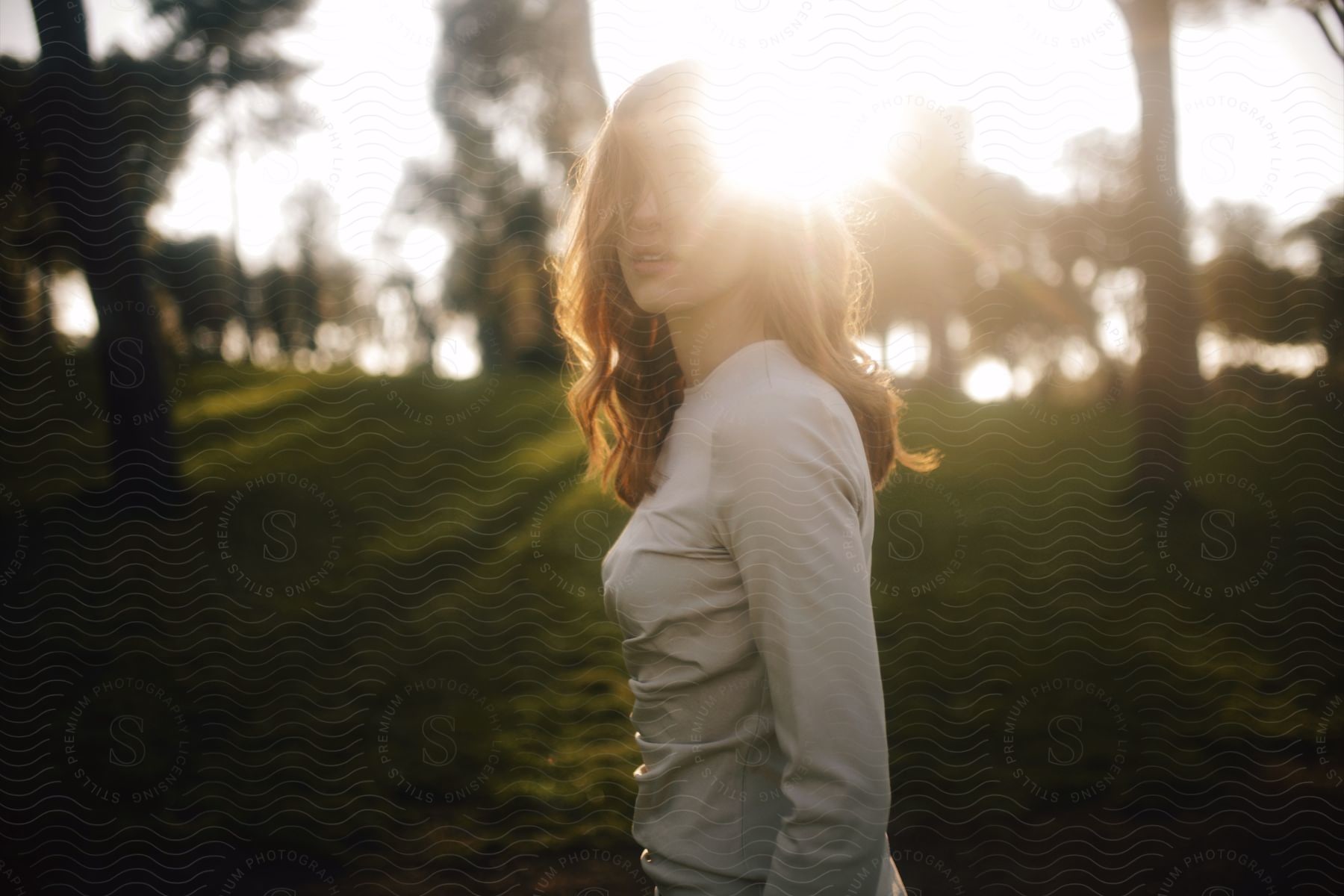 redhead woman wearing white clothes standing outdoors during day time with the sunlight distorting part of her face