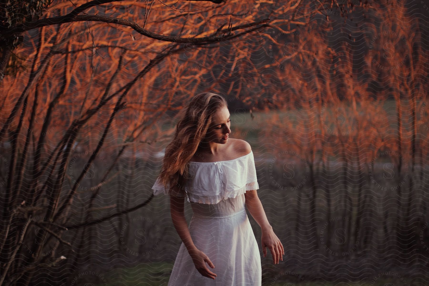 A women is posing out in nature as the sun sets.