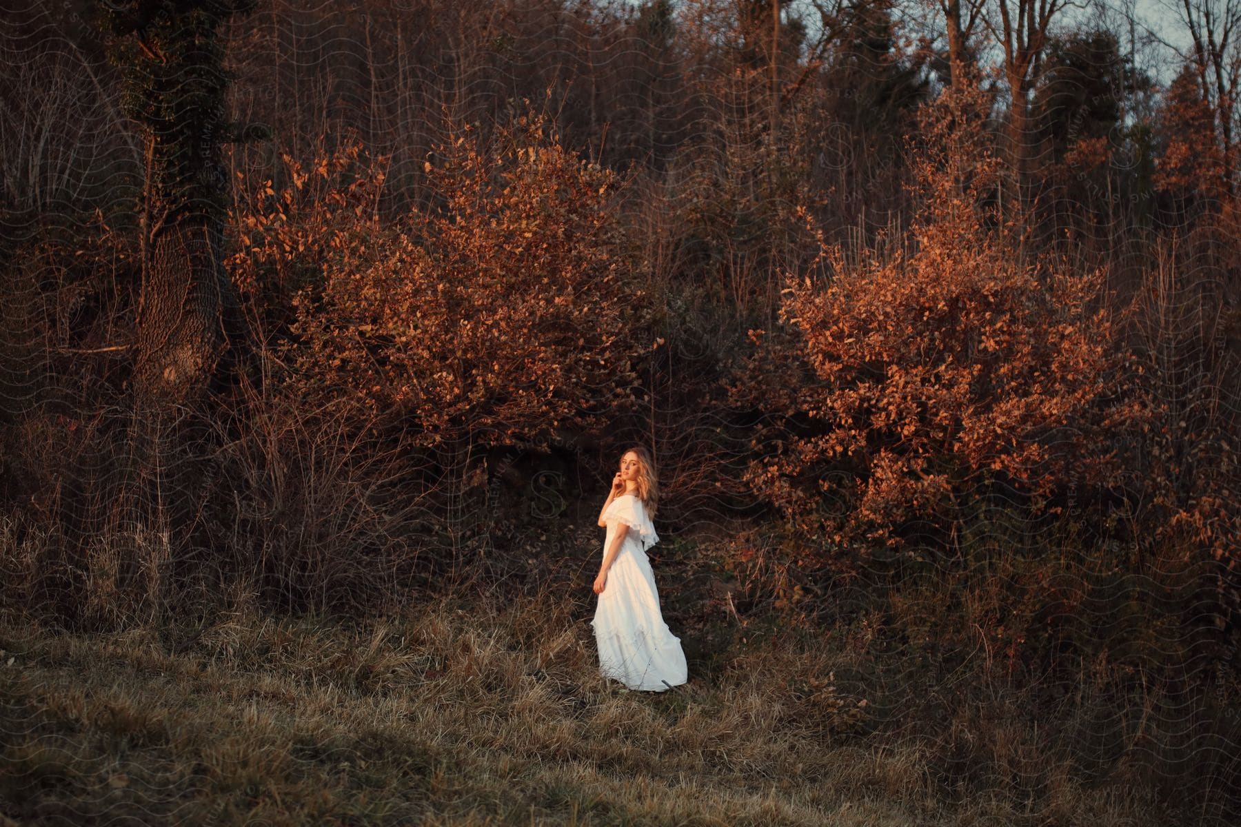 A women is standing outside while the sun is setting.