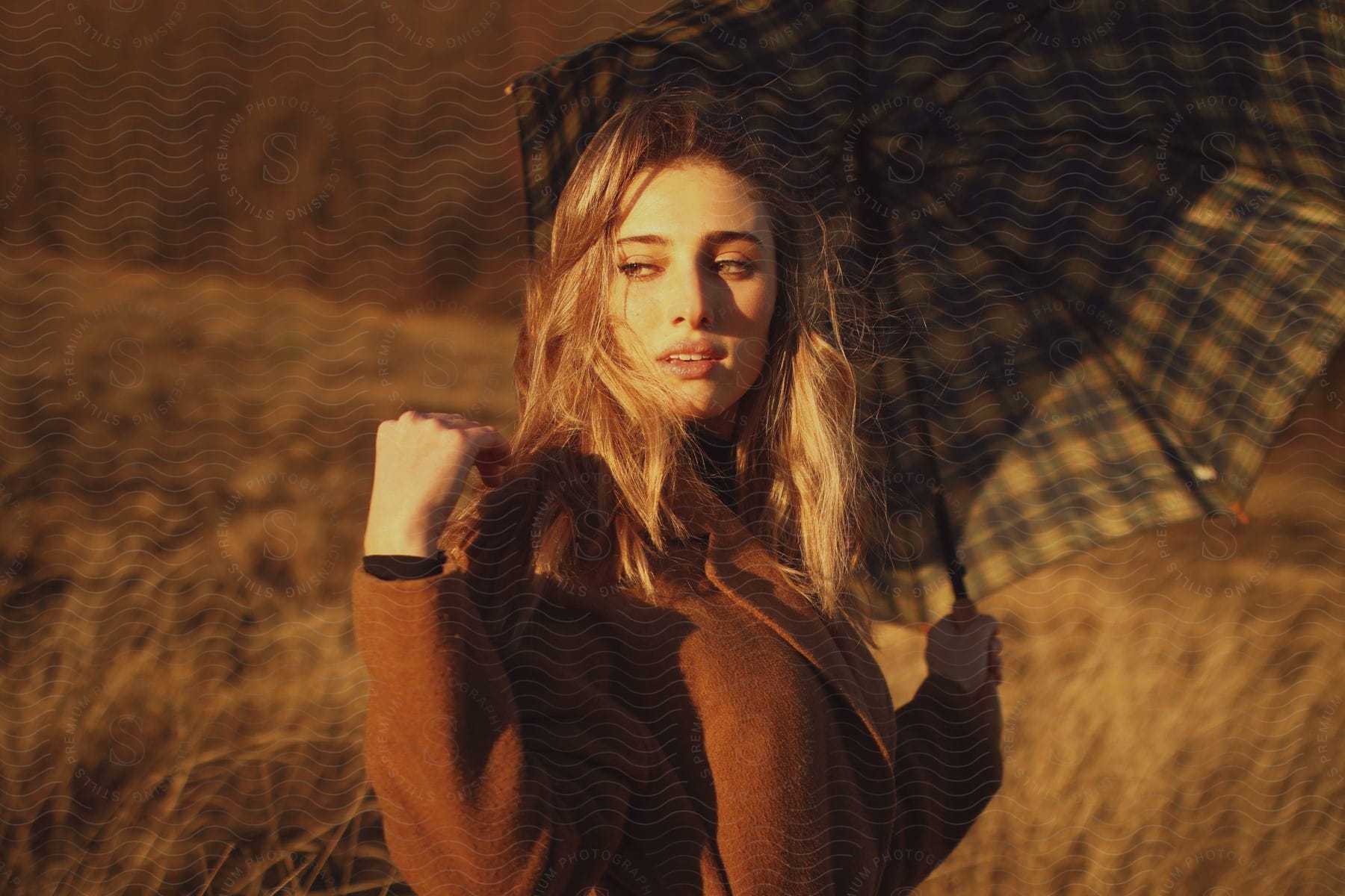 A woman modeling some clothes and umbrella outdoors.