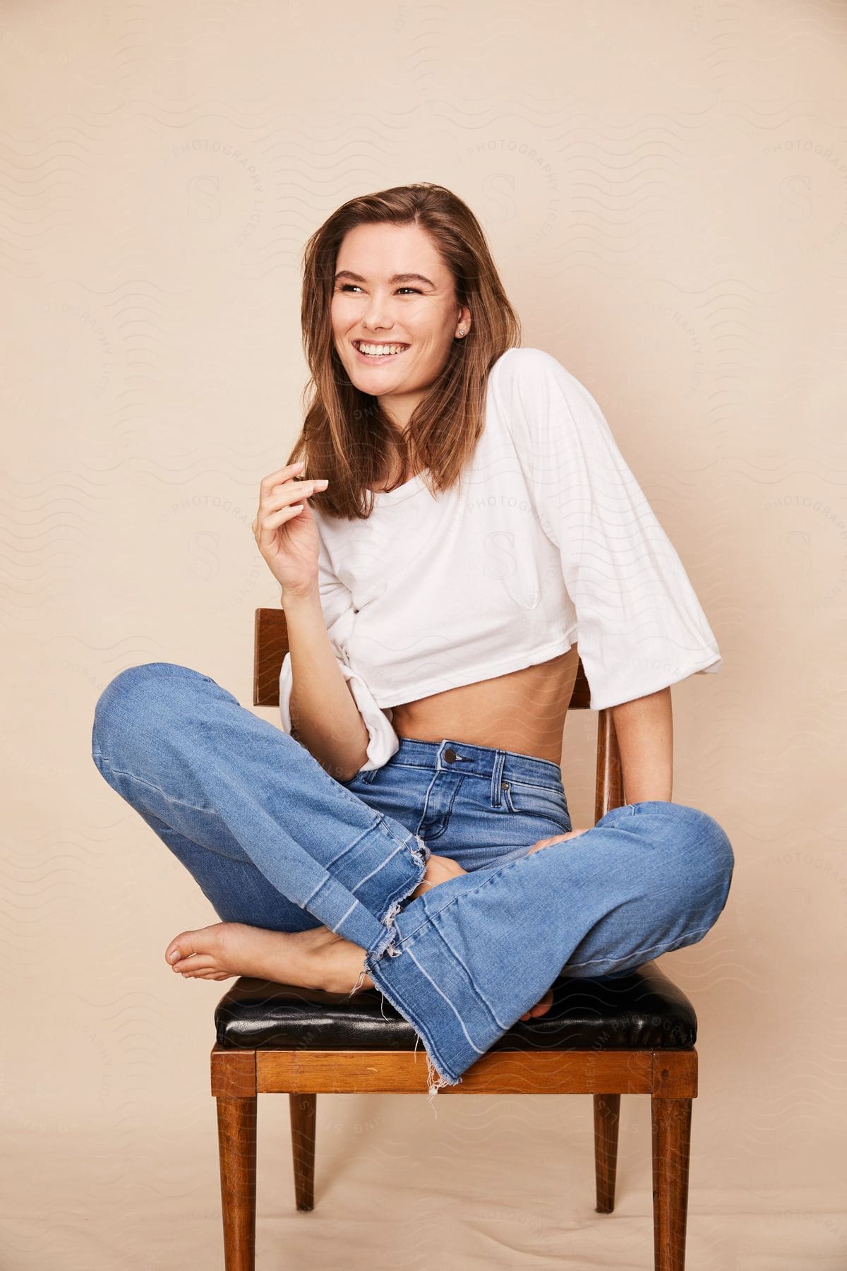 Smiling model sitting with crossed legs in a chair in a studio.