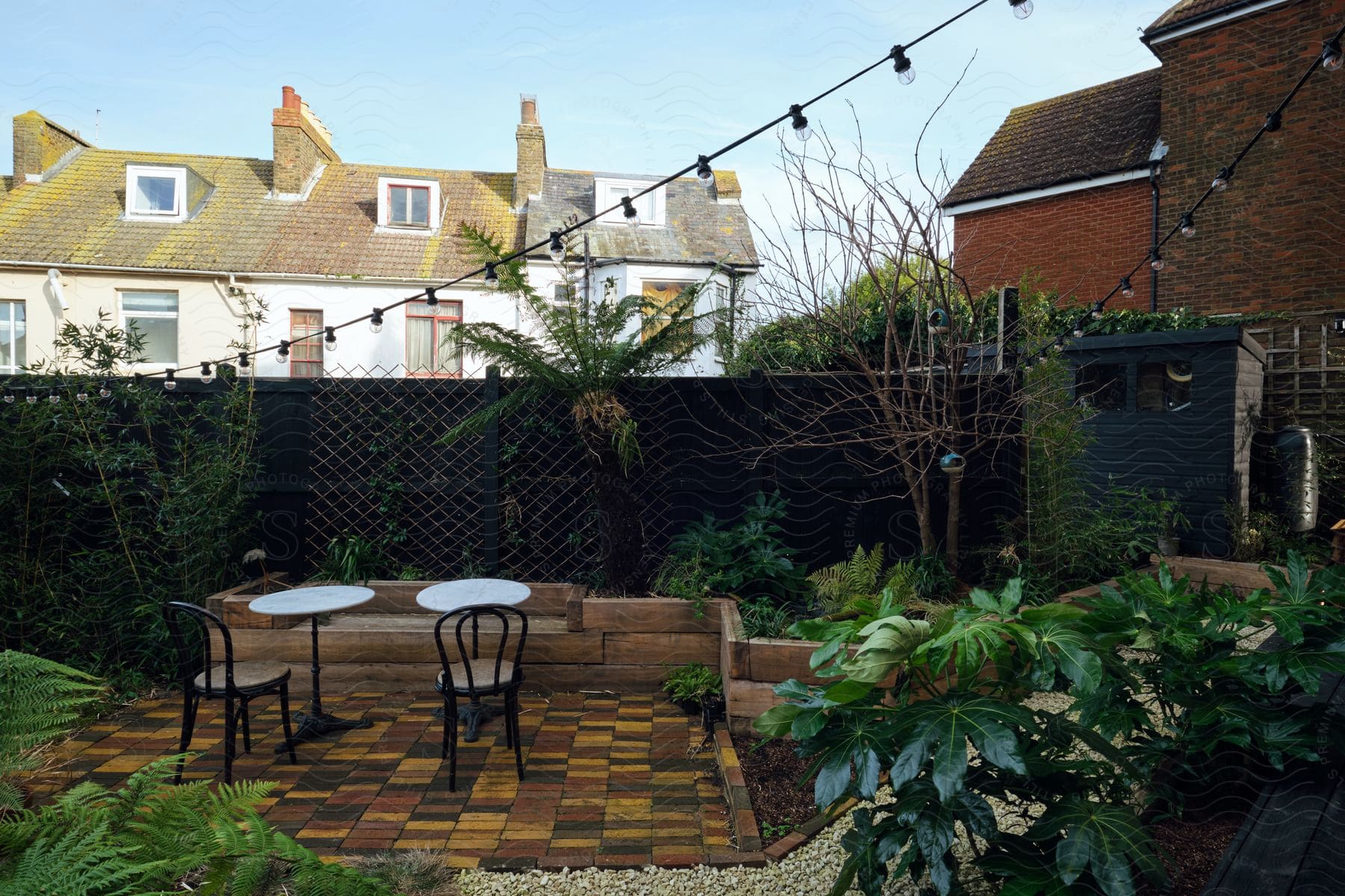 Architecture of the backyard of a house with a wooden deck with tables and a garden around it