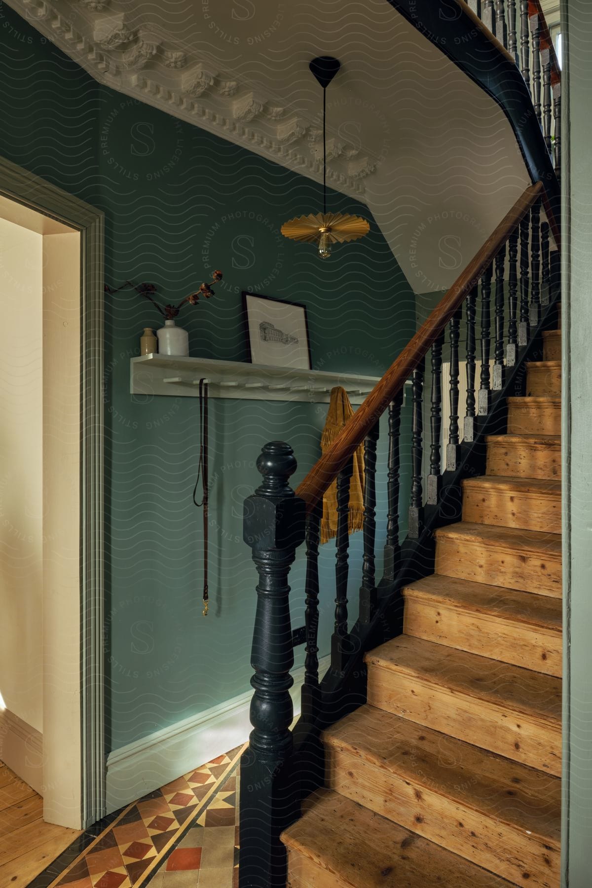 A staircase with a handrail painted dark green in a house.