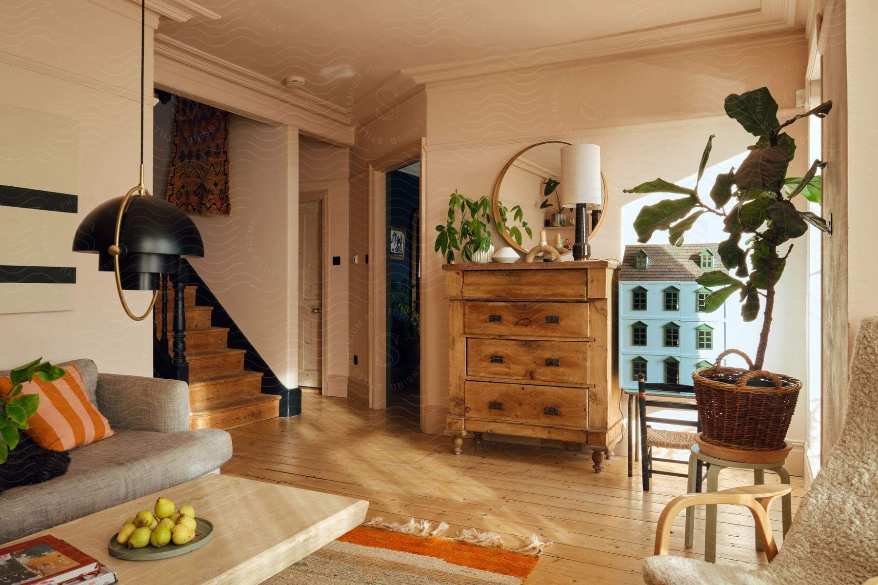 The interior of a home that has wood flooring is filled with furniture and a number of potted plants.