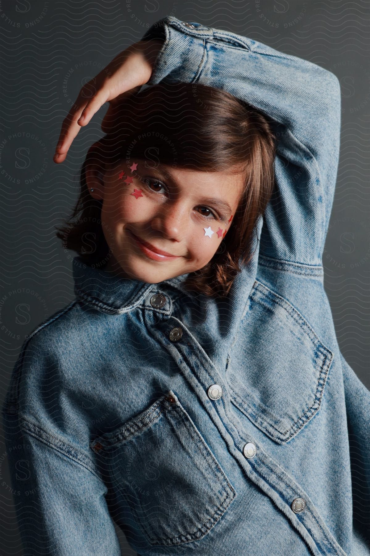 Portrait of a young little girl model posing with a denim jacket.