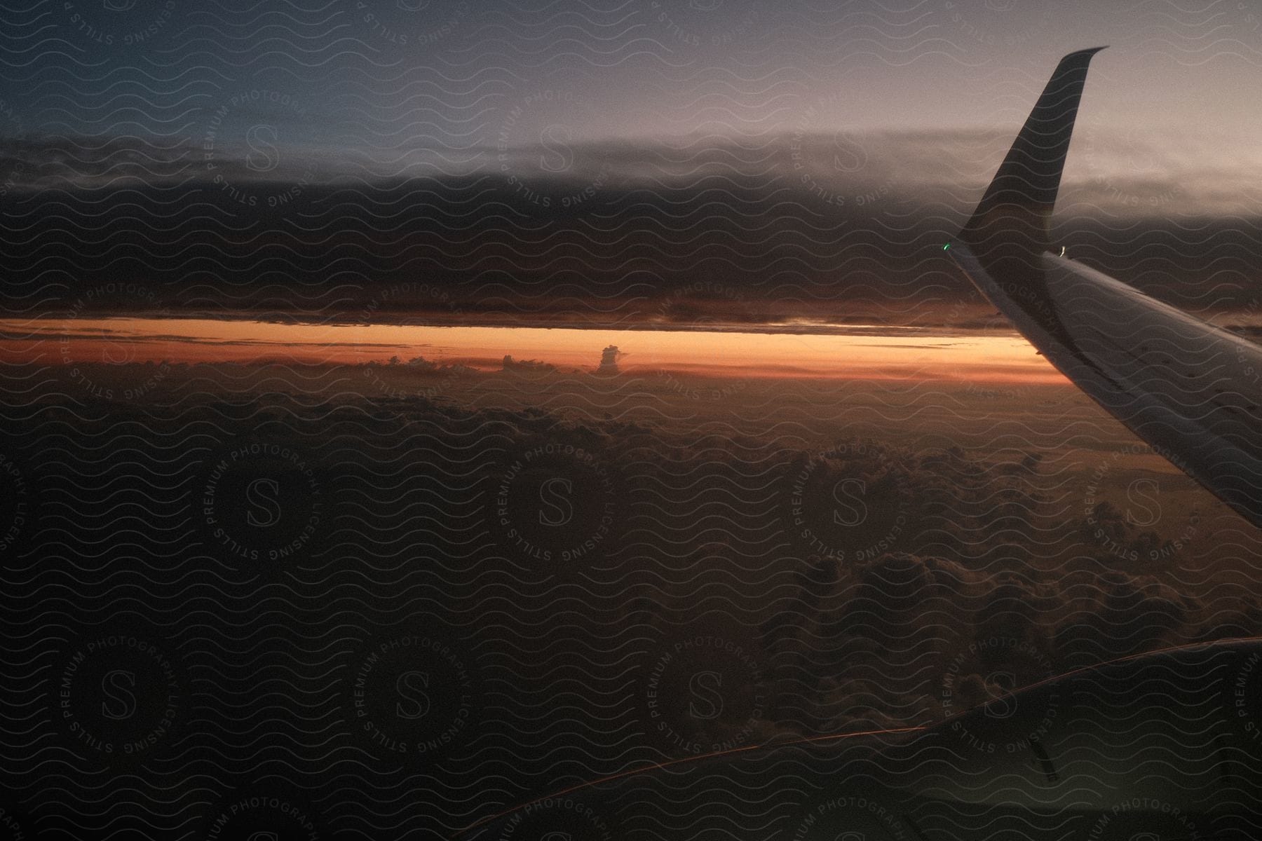 The tip of an airplane's wing, as it flies over the clouds at dawn.